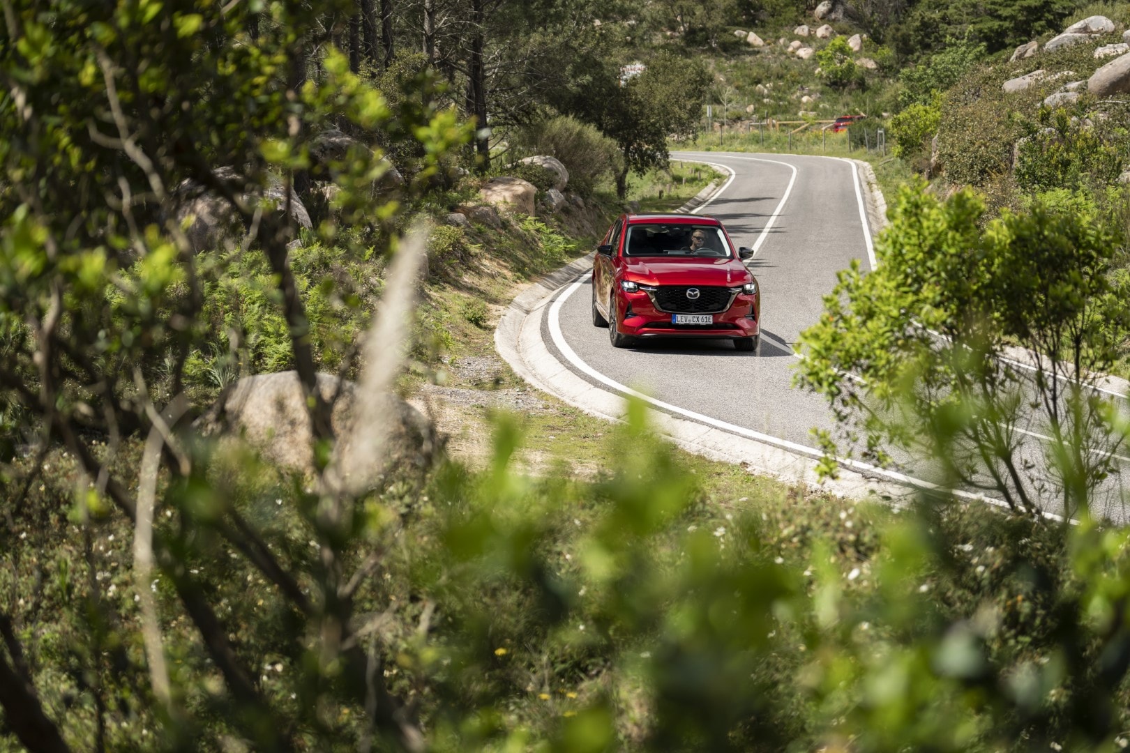 Trasera del CX-60 híbrido tomando una curva con elegancia y dinamismo.