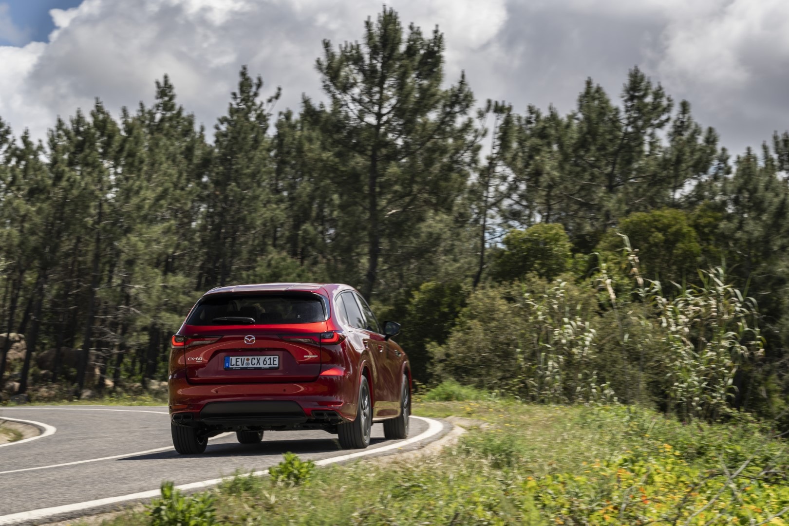 Imagen en curva resaltando la parte trasera y lateral del Mazda CX-60 en un entorno natural.