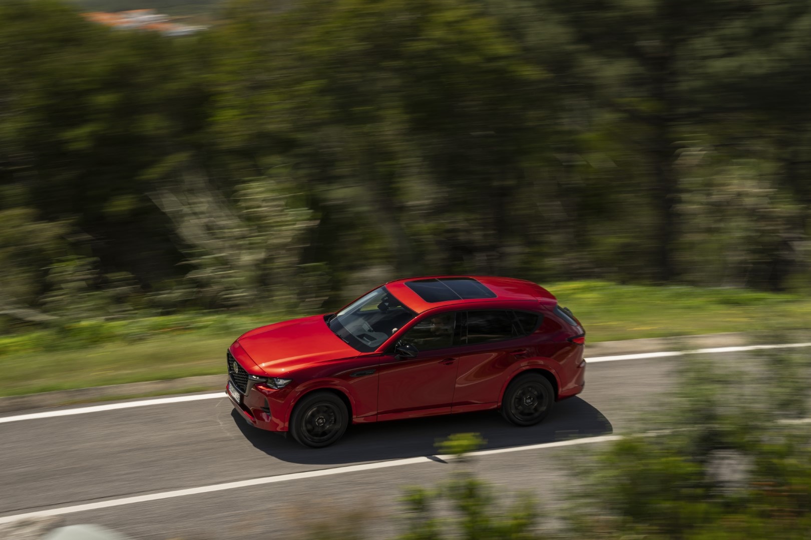 Perfil lateral del Mazda CX-60 en color rojo exhibiendo su línea de diseño y coloración vibrante.