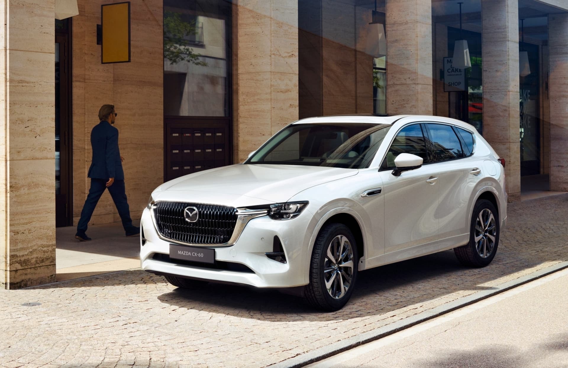 Mazda CX-60 blanco mostrado de costado en un escenario urbano, subrayando su elegancia.