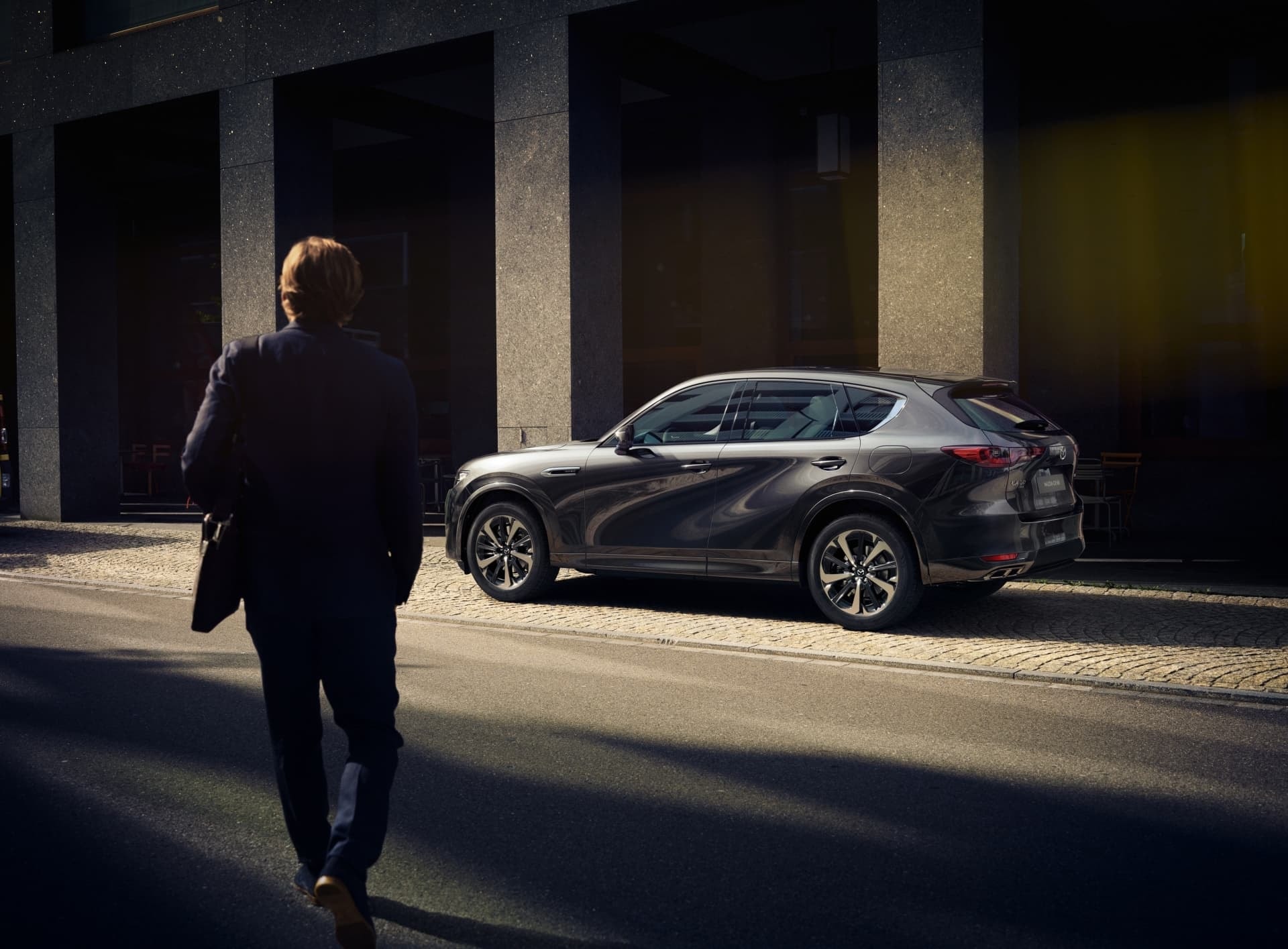 Una visión artística del Mazda CX-60 trasero en un entorno urbano al anochecer.