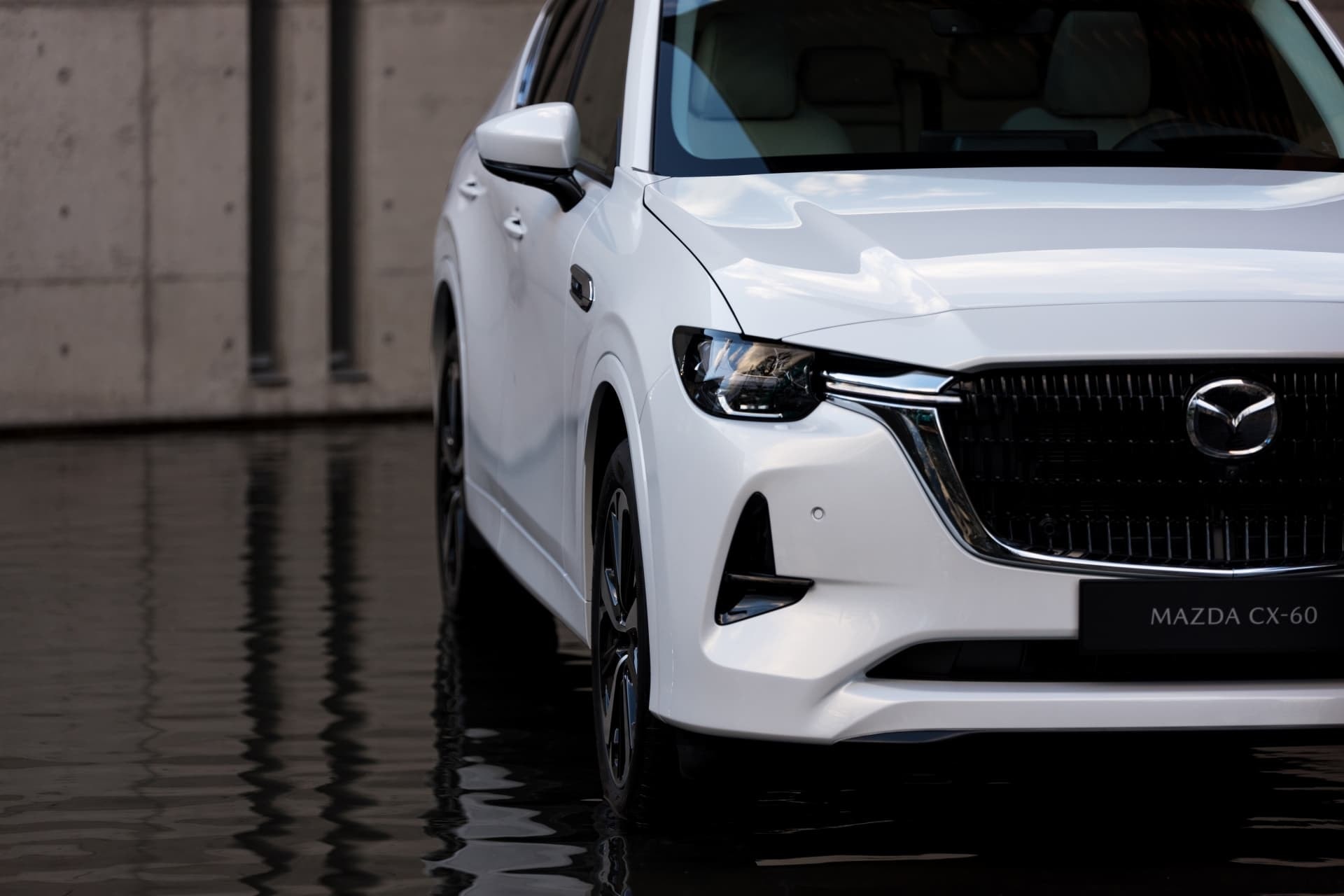 Vista delantera del Mazda CX-60 reflejado en el agua.