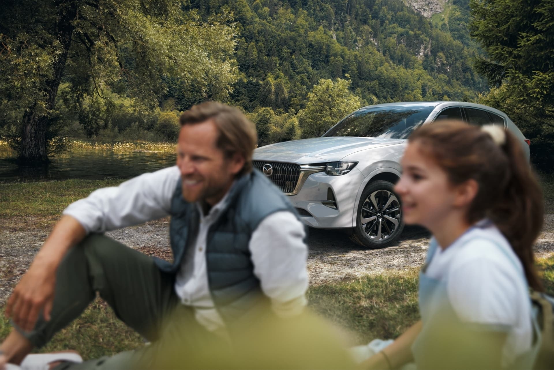 Foto desenfocada del Mazda CX-60, énfasis en las personas al frente.