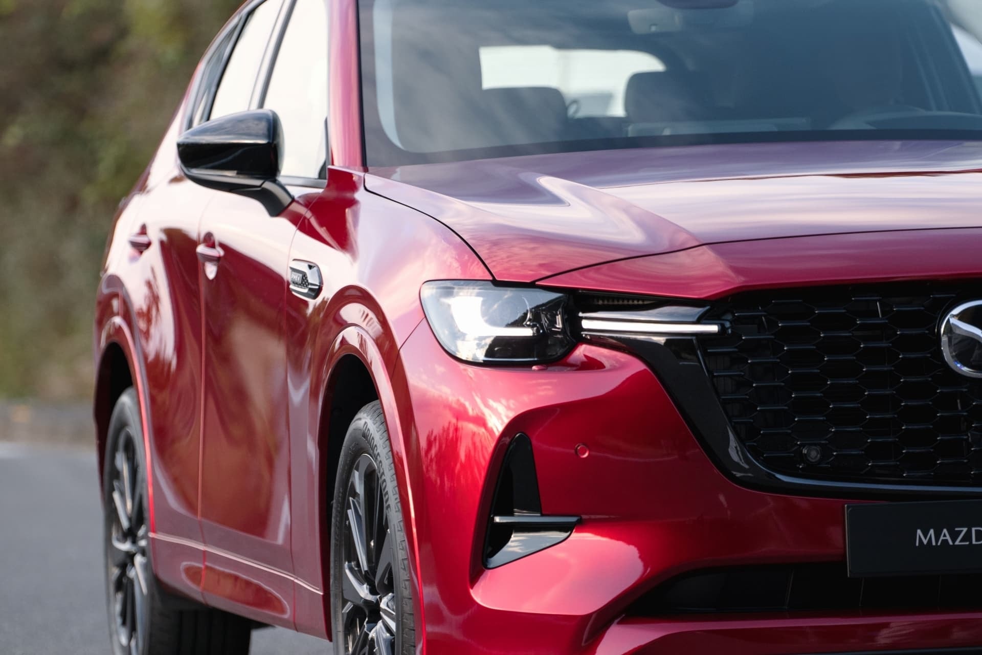 Detalle de la parrilla y faros delanteros del Mazda CX-60 en movimiento.