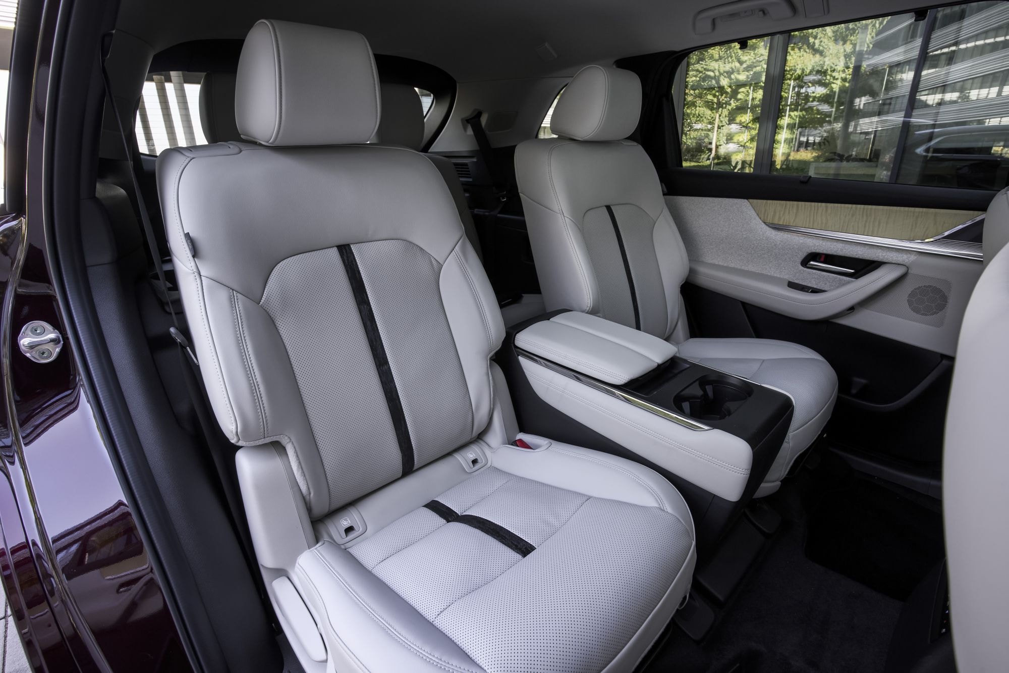 Vista de los cómodos asientos traseros del Mazda CX-80, en elegante tapicería blanca.