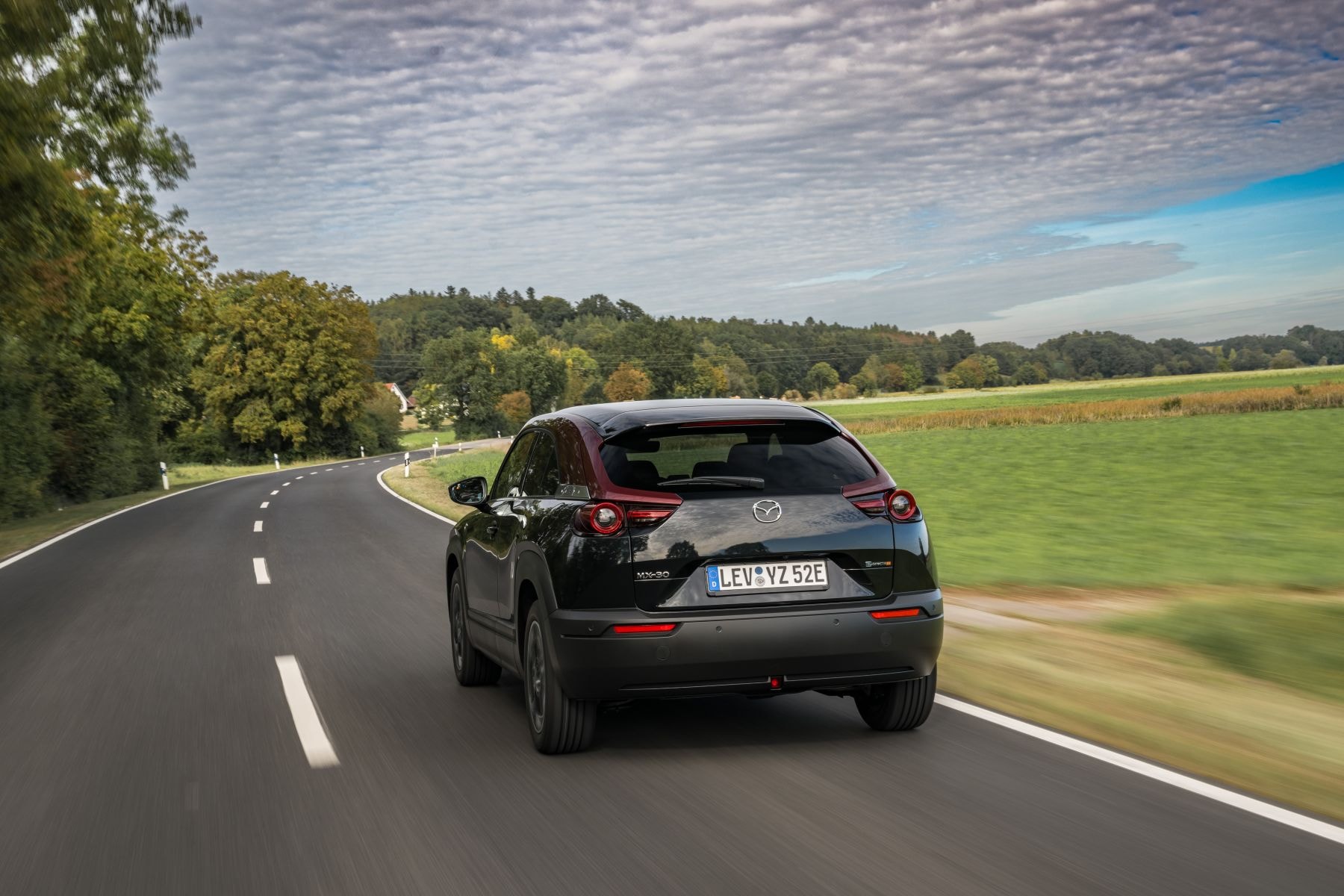 Otro ángulo del MX-30 Híbrido en una vía urbana, destacando su silueta.