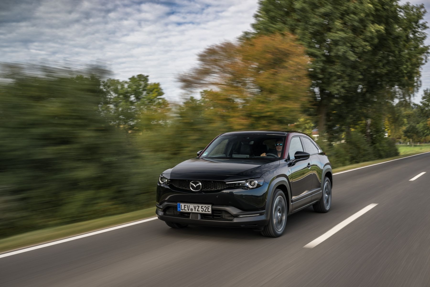 Vista trasera del Mazda MX-30 Híbrido en una carretera rural.