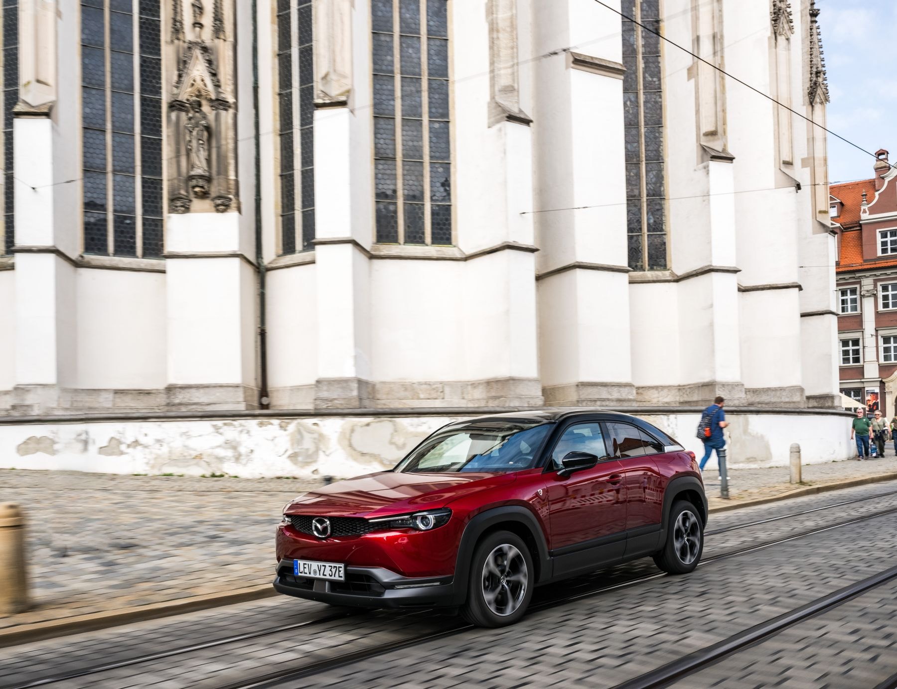 Un elegante Mazda MX-30 circulando cerca de una emblemática catedral.