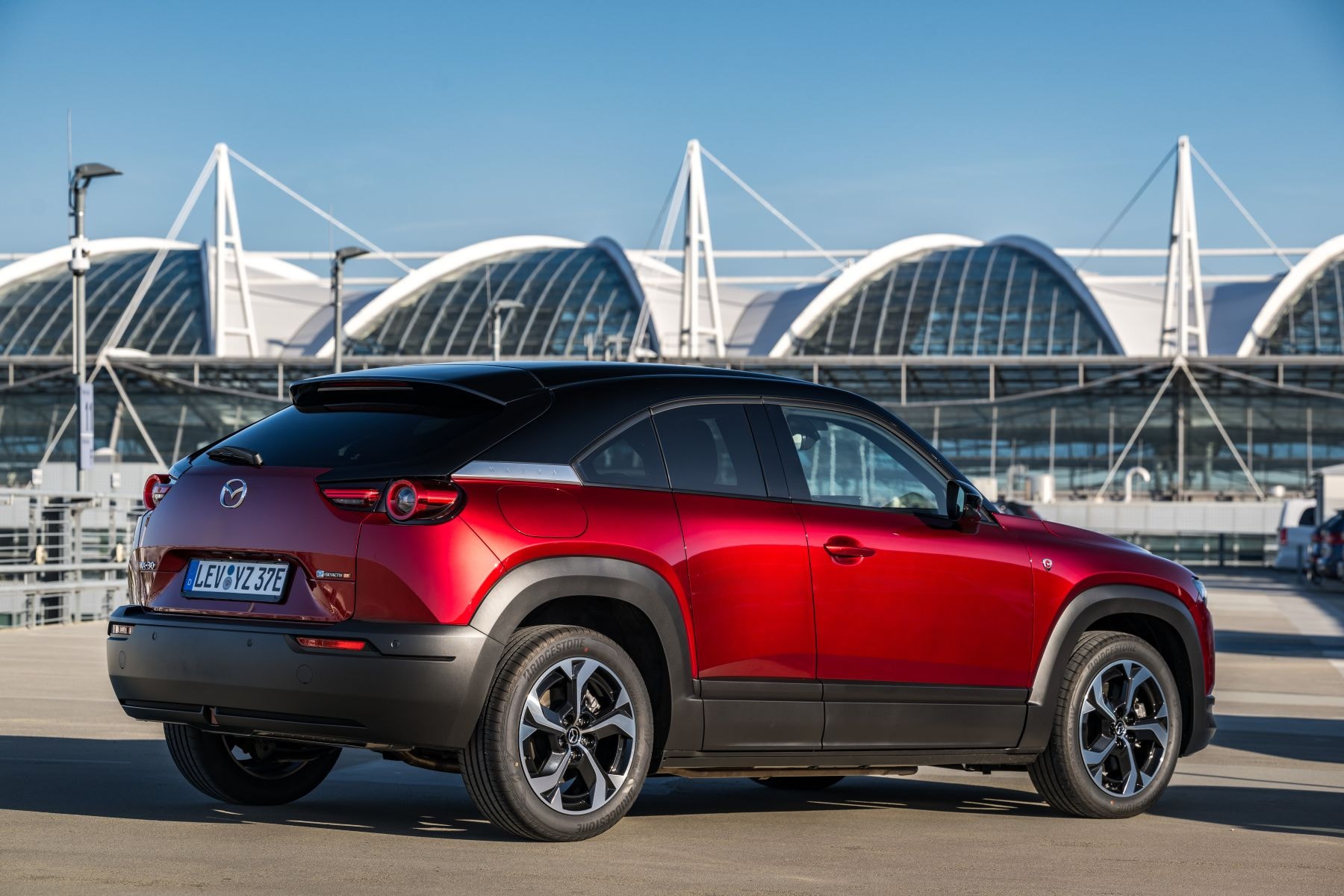 Perspectiva trasera del Mazda MX-30 eléctrico en un entorno urbano.