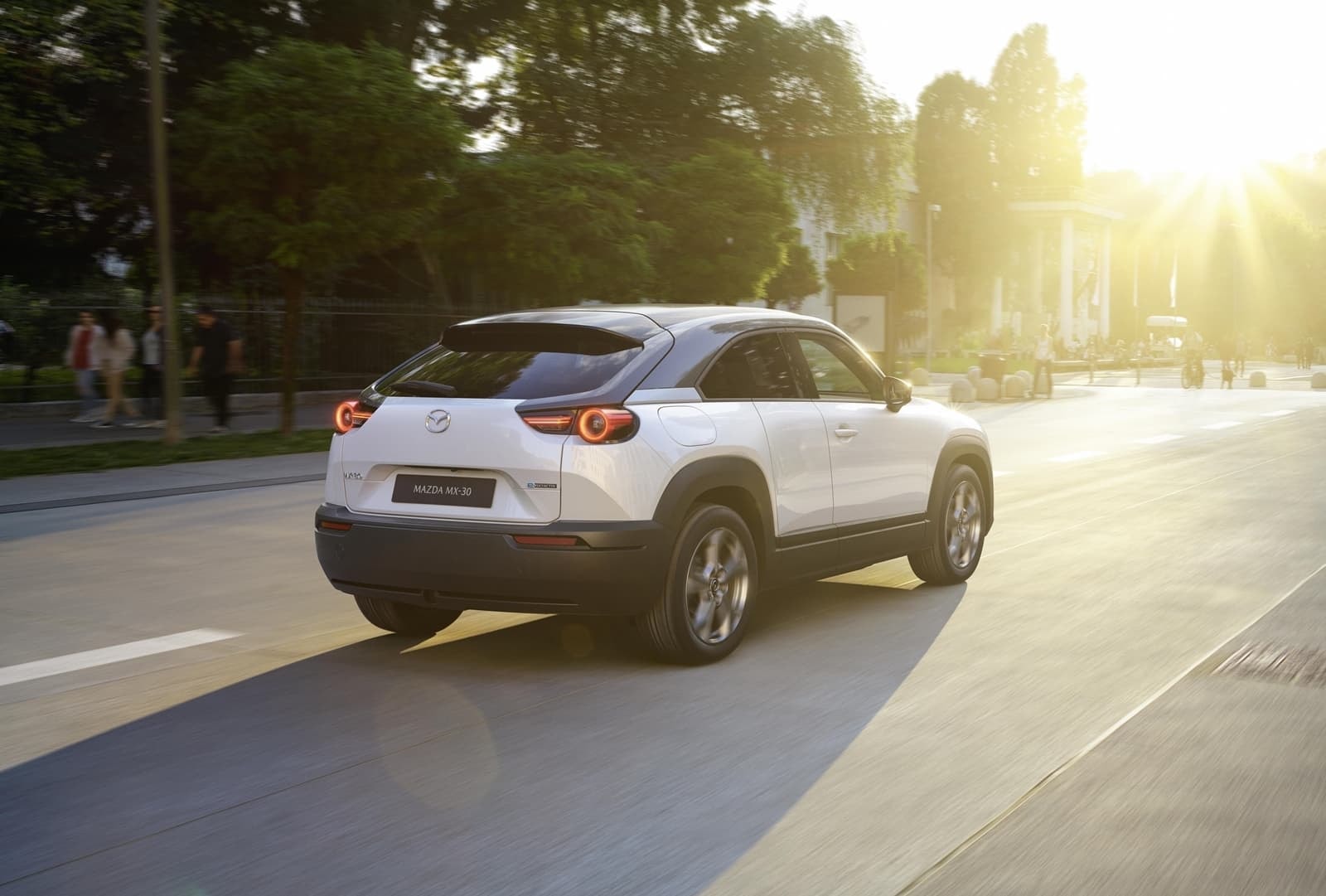 Perspectiva trasera del Mazda MX-30 circulando en un entorno urbano.