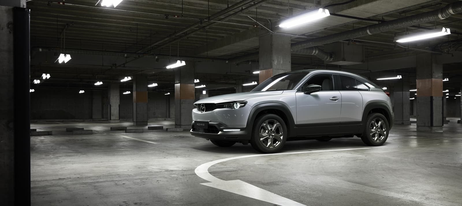Vista lateral del Mazda MX-30 en un estacionamiento subterráneo.