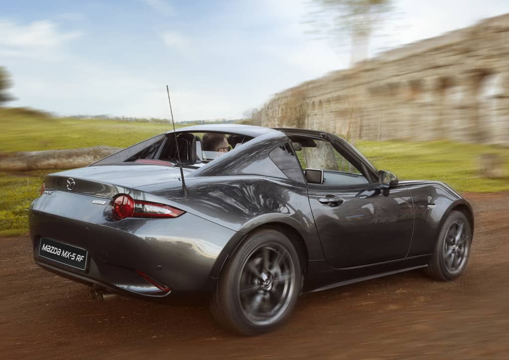 Vista trasera y lateral del Mazda MX-5 RF en carretera abierta.