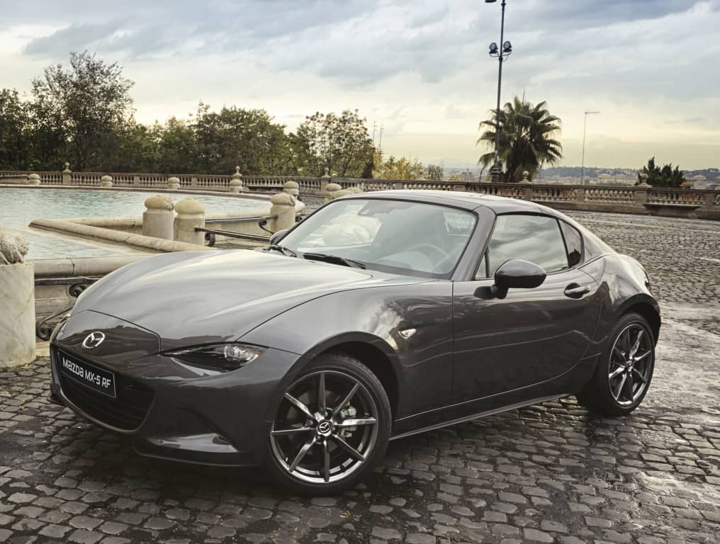 Ángulo frontal y lateral del Mazda MX-5 RF cerca de una estatua.