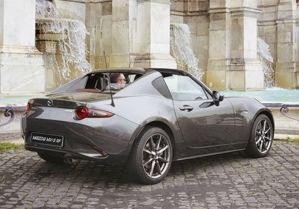 Vista lateral del Mazda MX-5 RF junto a una fuente histórica.