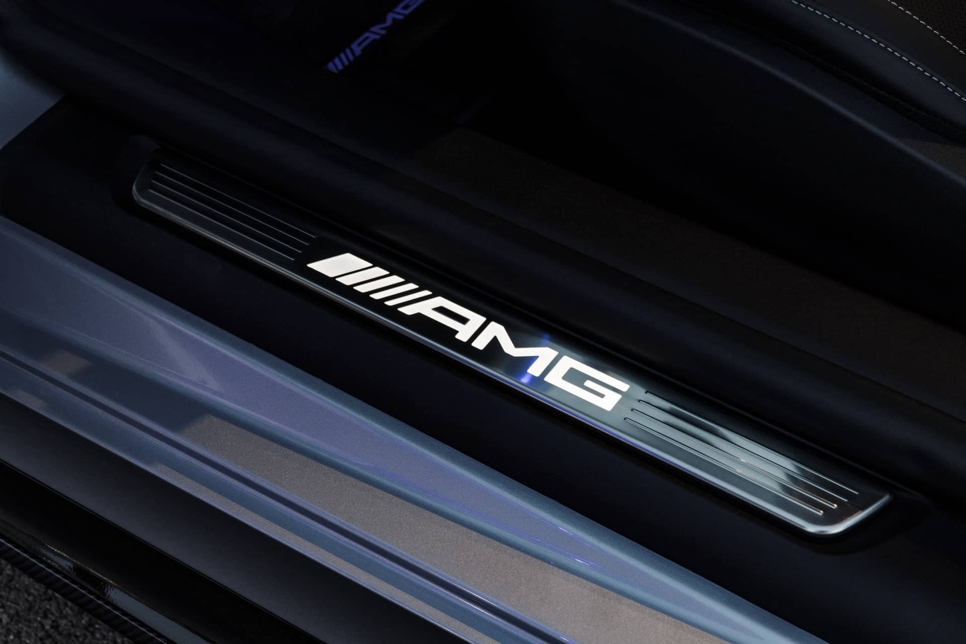 Detalle del umbral de puerta iluminado con la insignia AMG, un toque de exclusividad.
