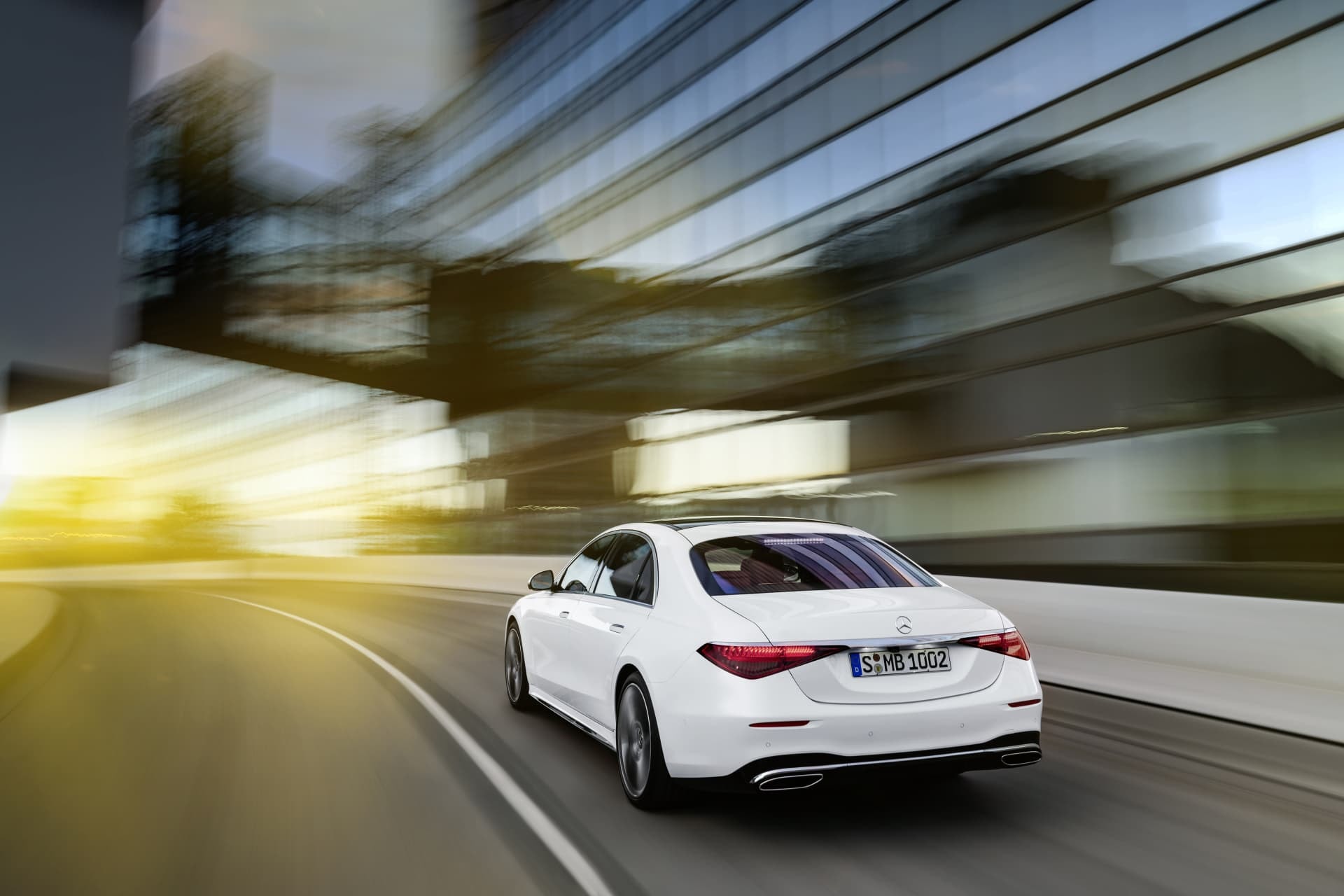 Perspectiva trasera de un Mercedes Clase S en movimiento por la ciudad.
