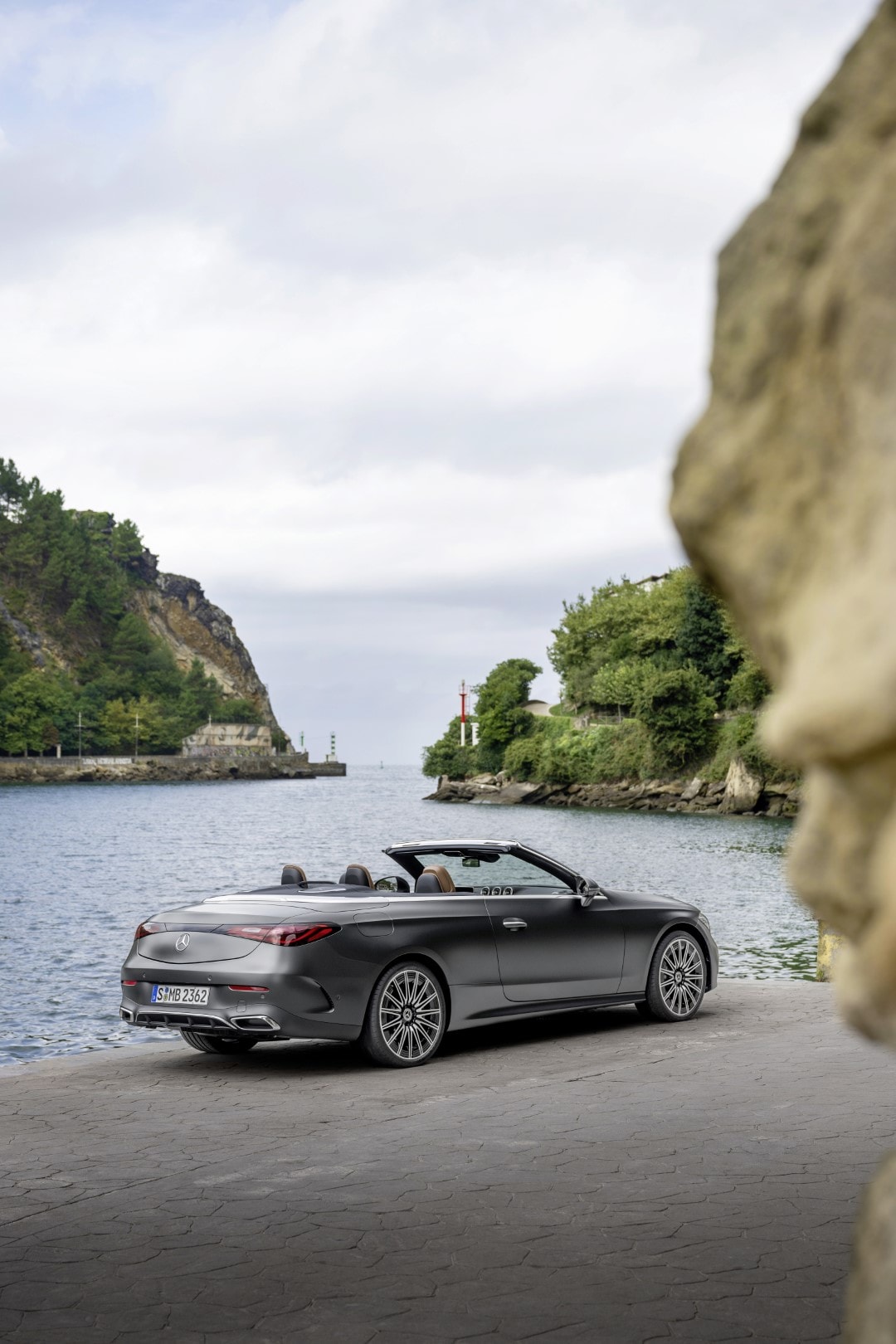 Perspectiva trasera del Mercedes CLE Cabrio con un escenario costero de fondo.
