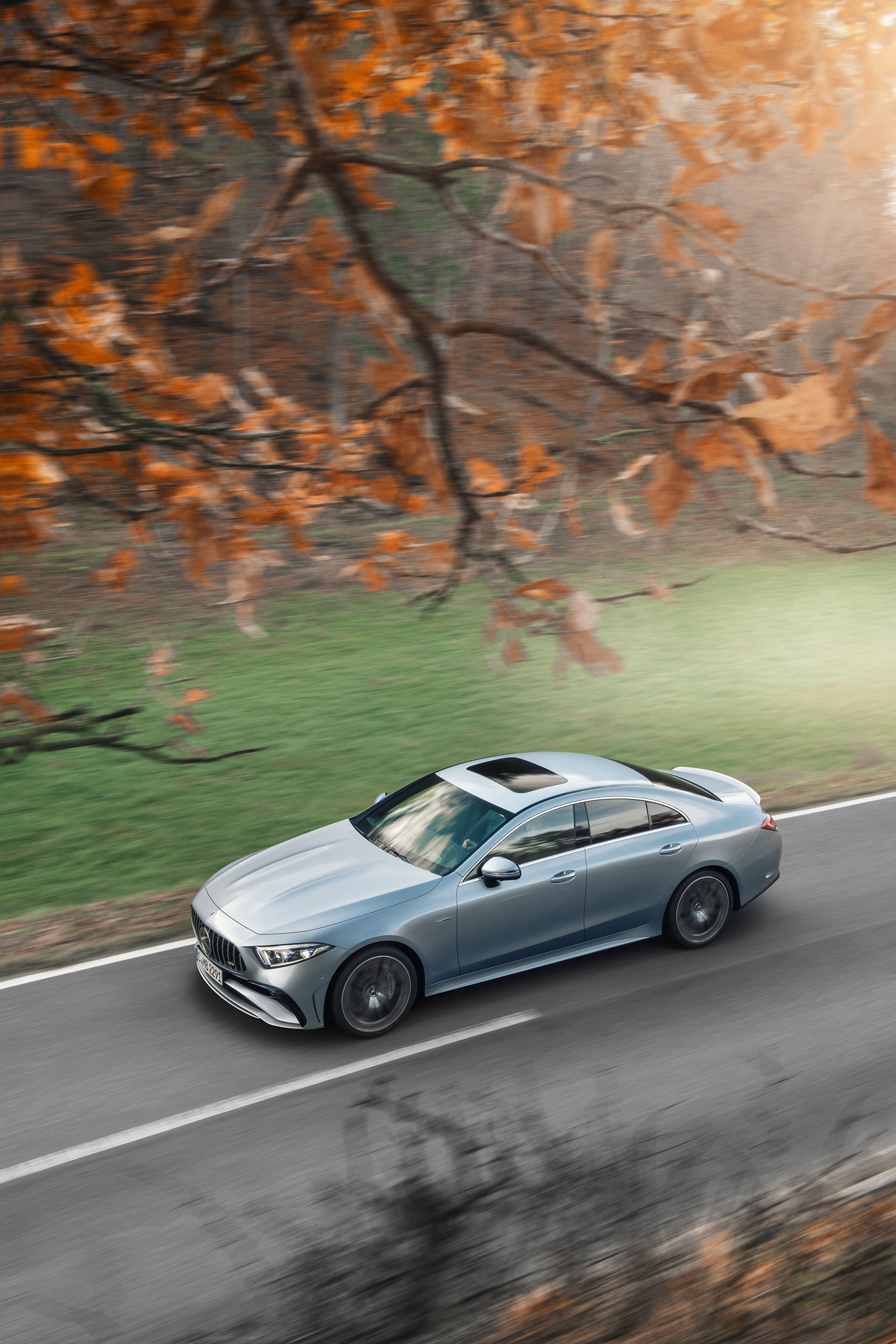 Vista aérea de un Mercedes CLS recorriendo una carretera otoñal
