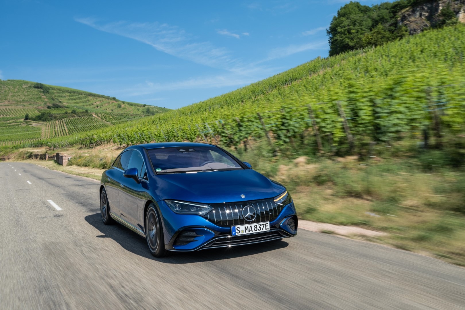 Imagen dinámica del Mercedes EQE en azul recorriendo una carretera.