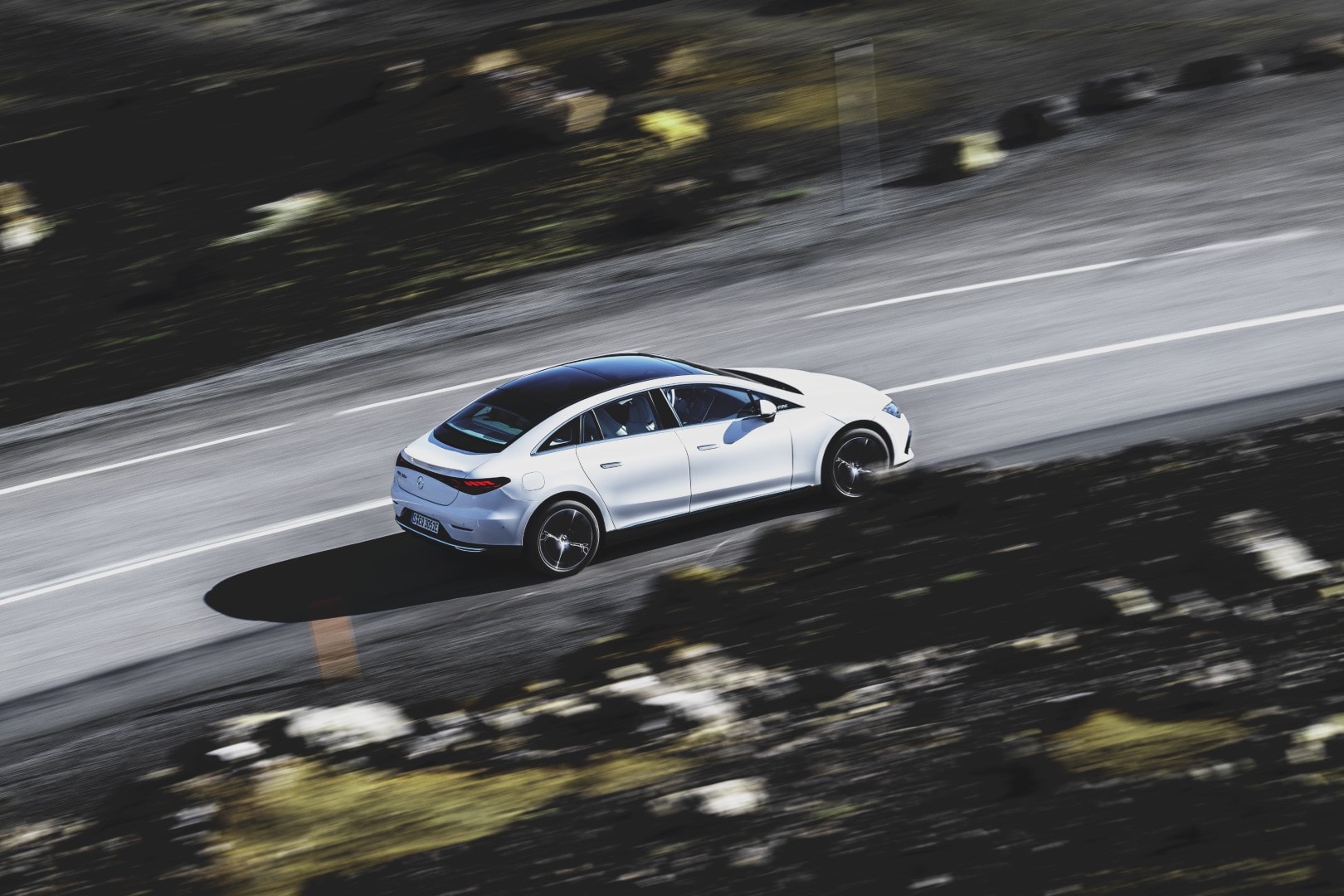 Toma en movimiento del Mercedes EQE mostrando su perfil lateral en carretera