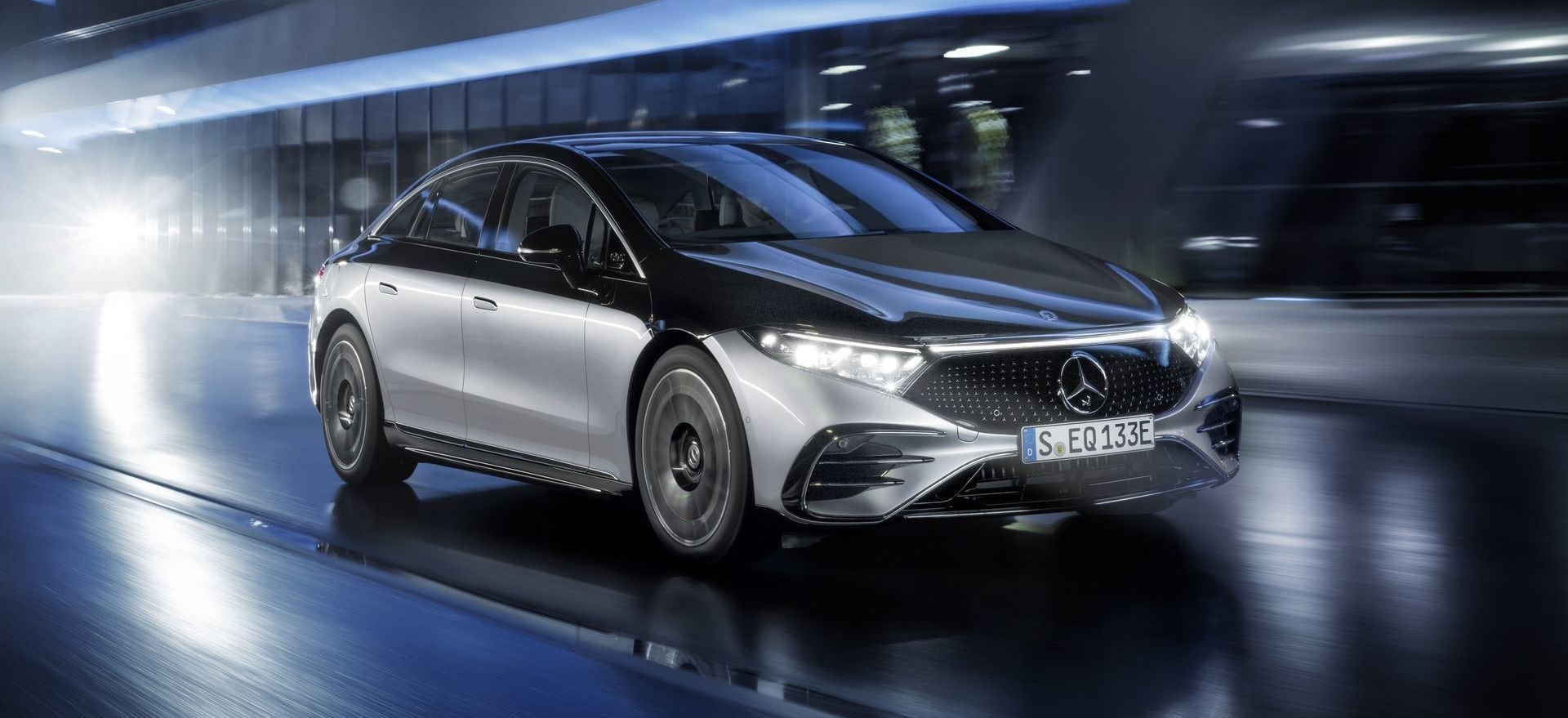 Mercedes EQS en movimiento, iluminación destacada, diseño aerodinámico.