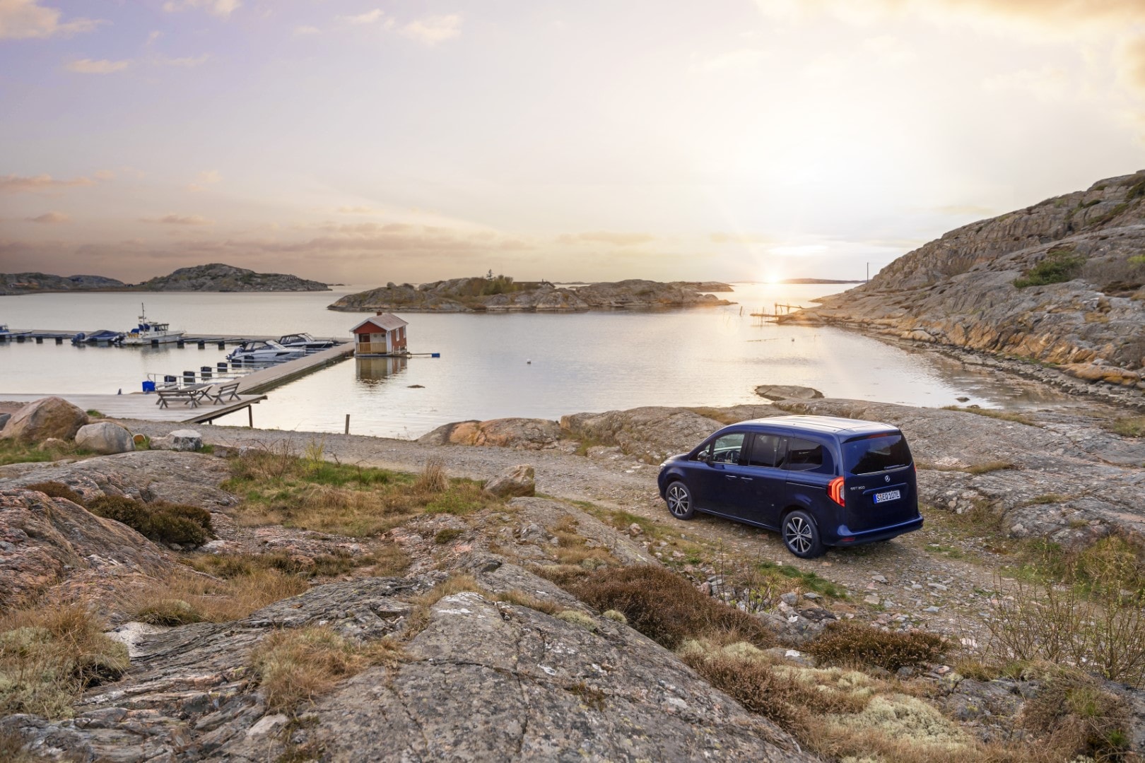 Un atardecer escénico resalta la silueta del Mercedes EQT, transmitiendo un aire de aventura y exploración.