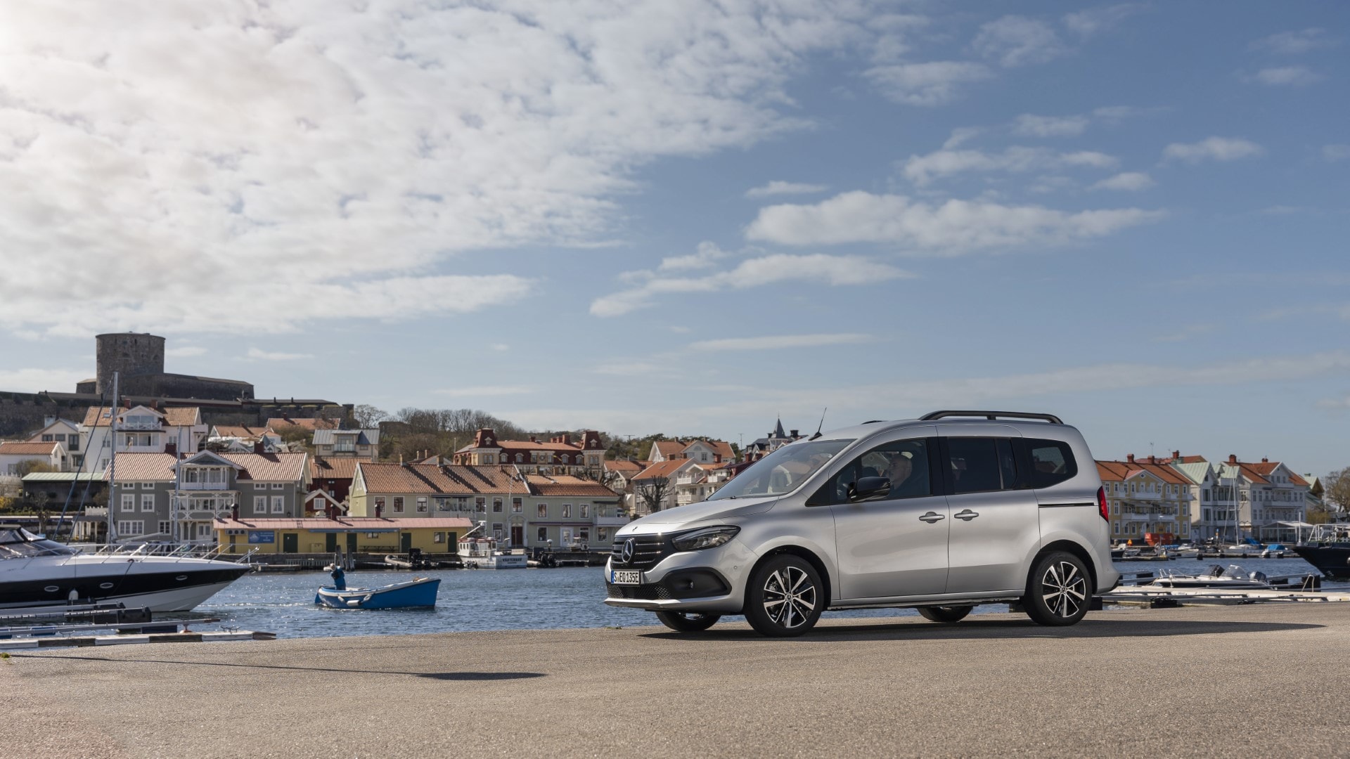 Mercedes EQT estacionado en un puerto, mostrando su lateral y entorno marítimo.