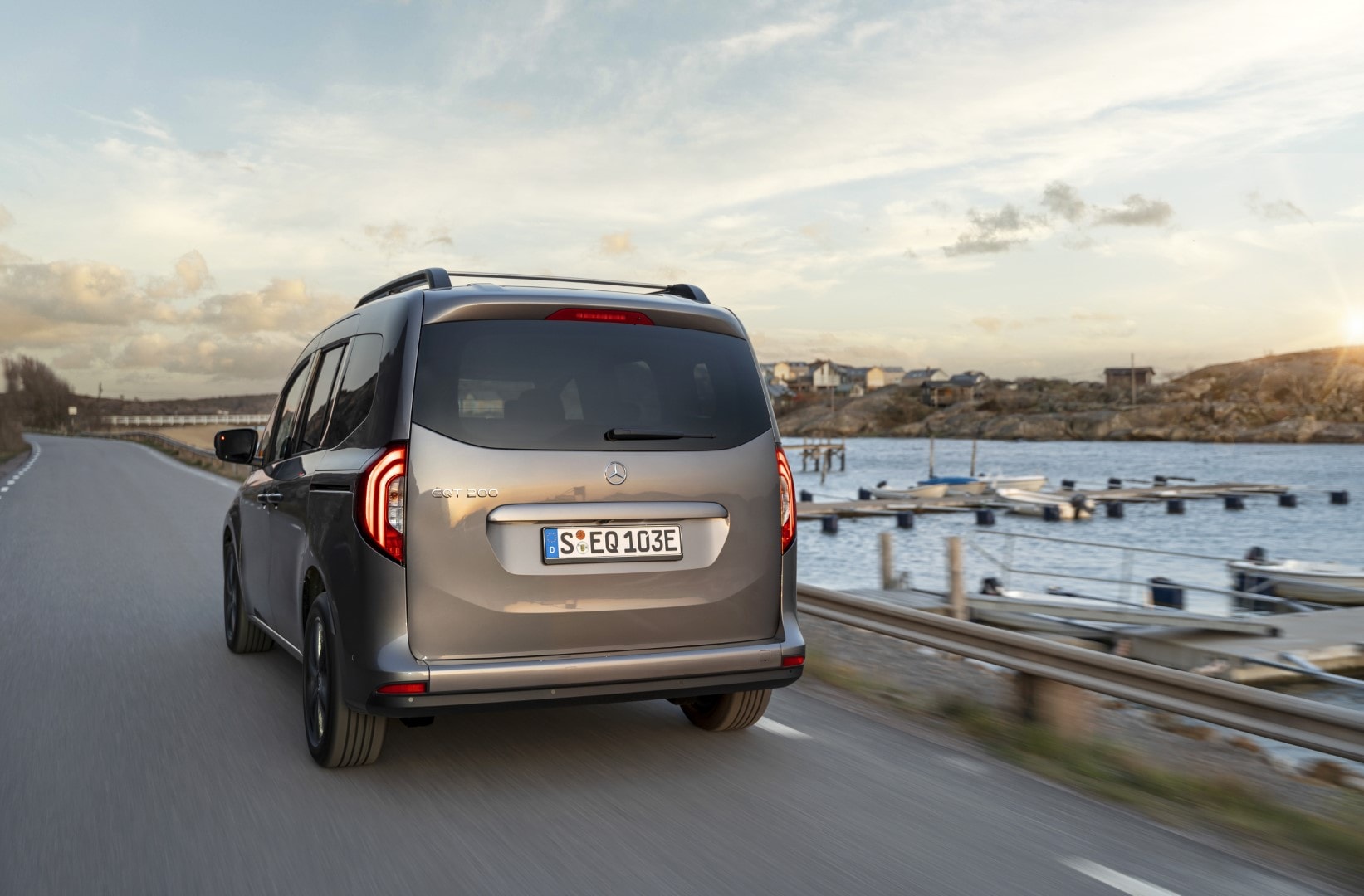 Perspectiva trasera del Mercedes EQT rodando en carretera con paisaje costero.