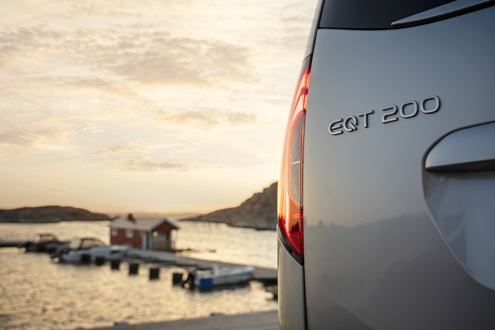 Vista trasera del Mercedes EQT con el logo y modelo en detalle, en un escenario costero.