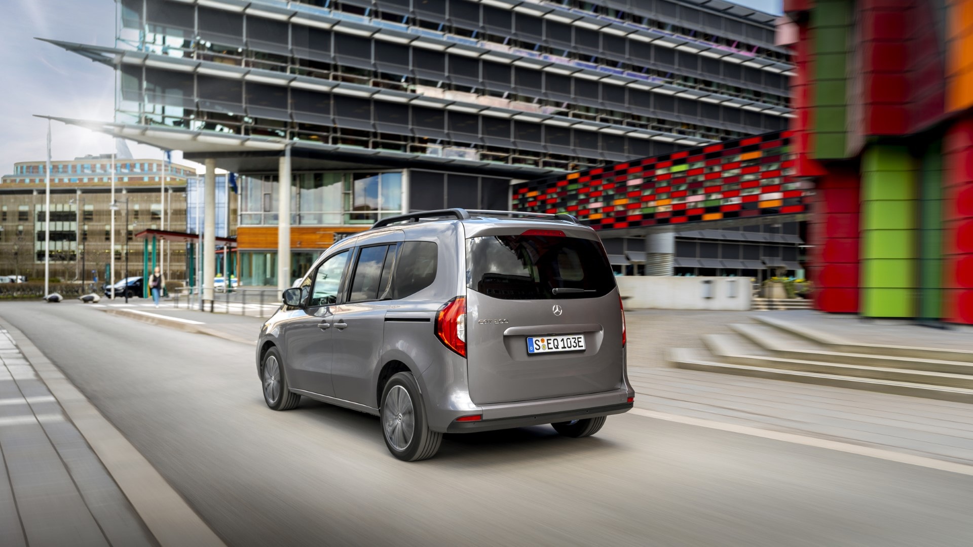 Vista trasera lateral del Mercedes EQT en un contexto urbano con arquitectura colorida.