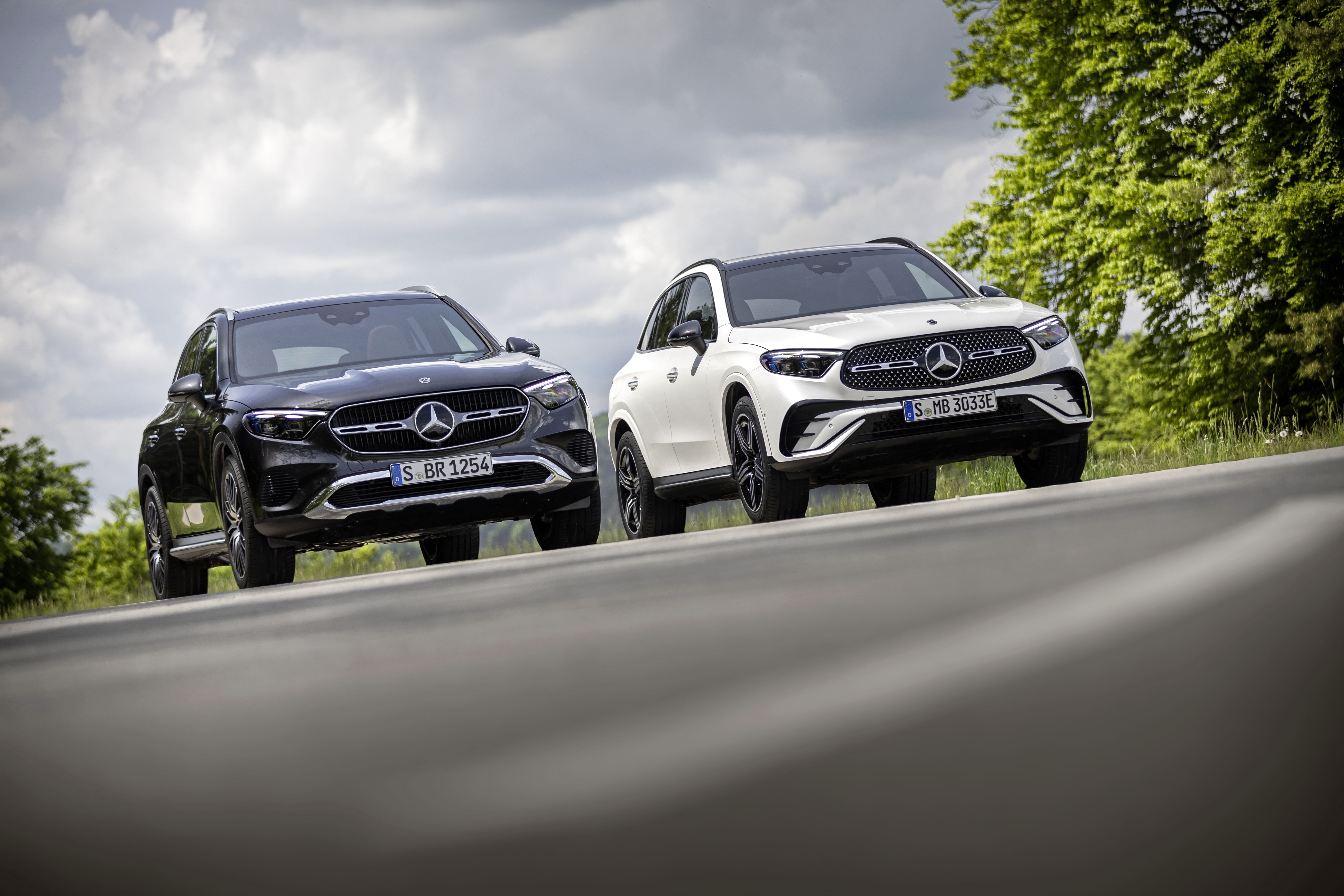 Comparación en ruta de dos modelos Mercedes GLC híbridos, destacando su diseño elegante.