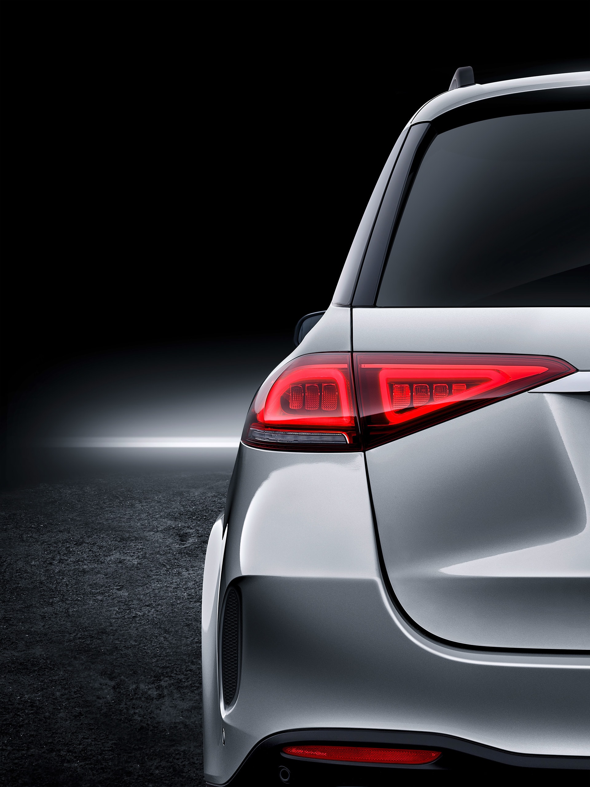 Enfoque en los pilotos traseros del Mercedes GLE en penumbra.