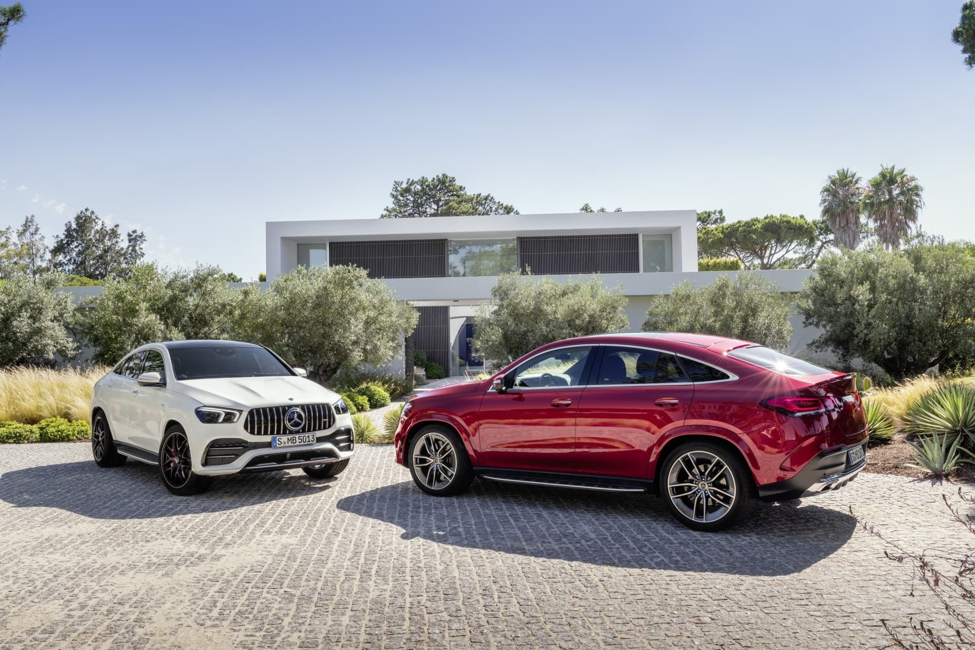 Dos modelos del Mercedes GLE frente a una residencia moderna.