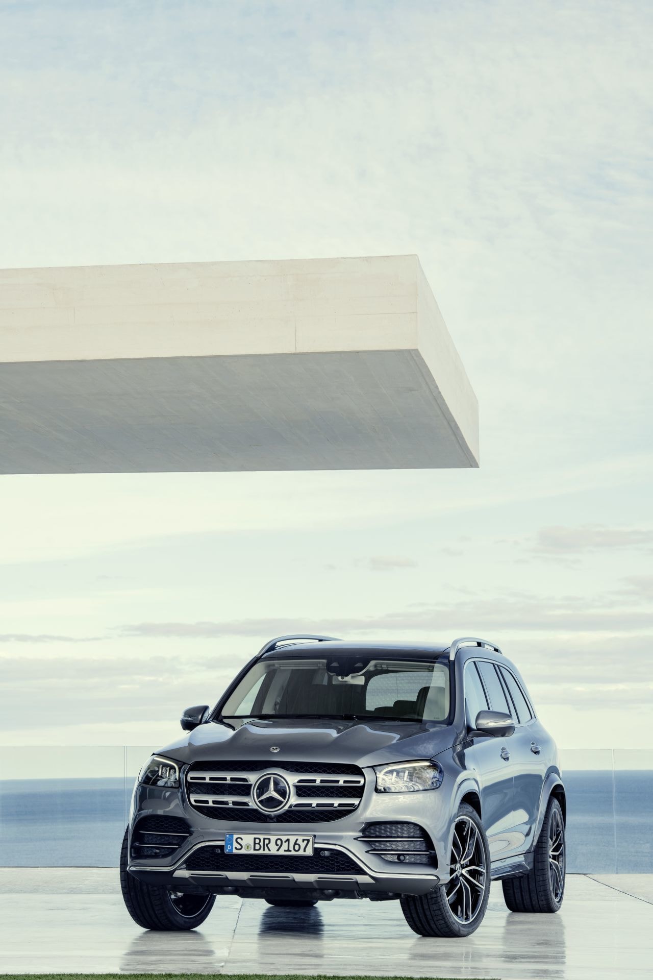Enfoque frontal del Mercedes GLS estacionado con fondo de arquitectura vanguardista.