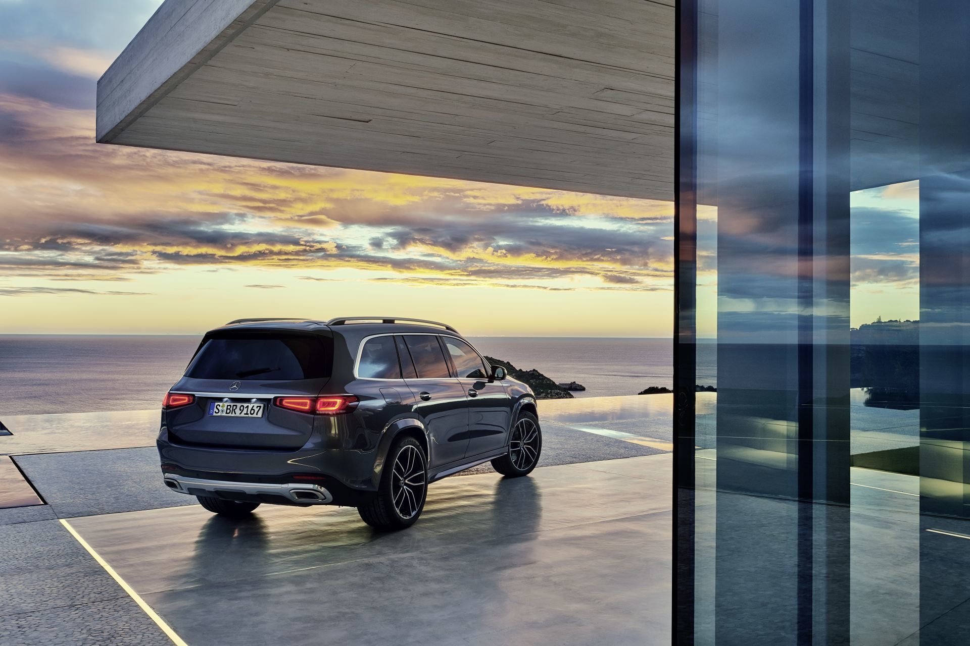 Mercedes GLS reflejado en una superficie acuática al atardecer.