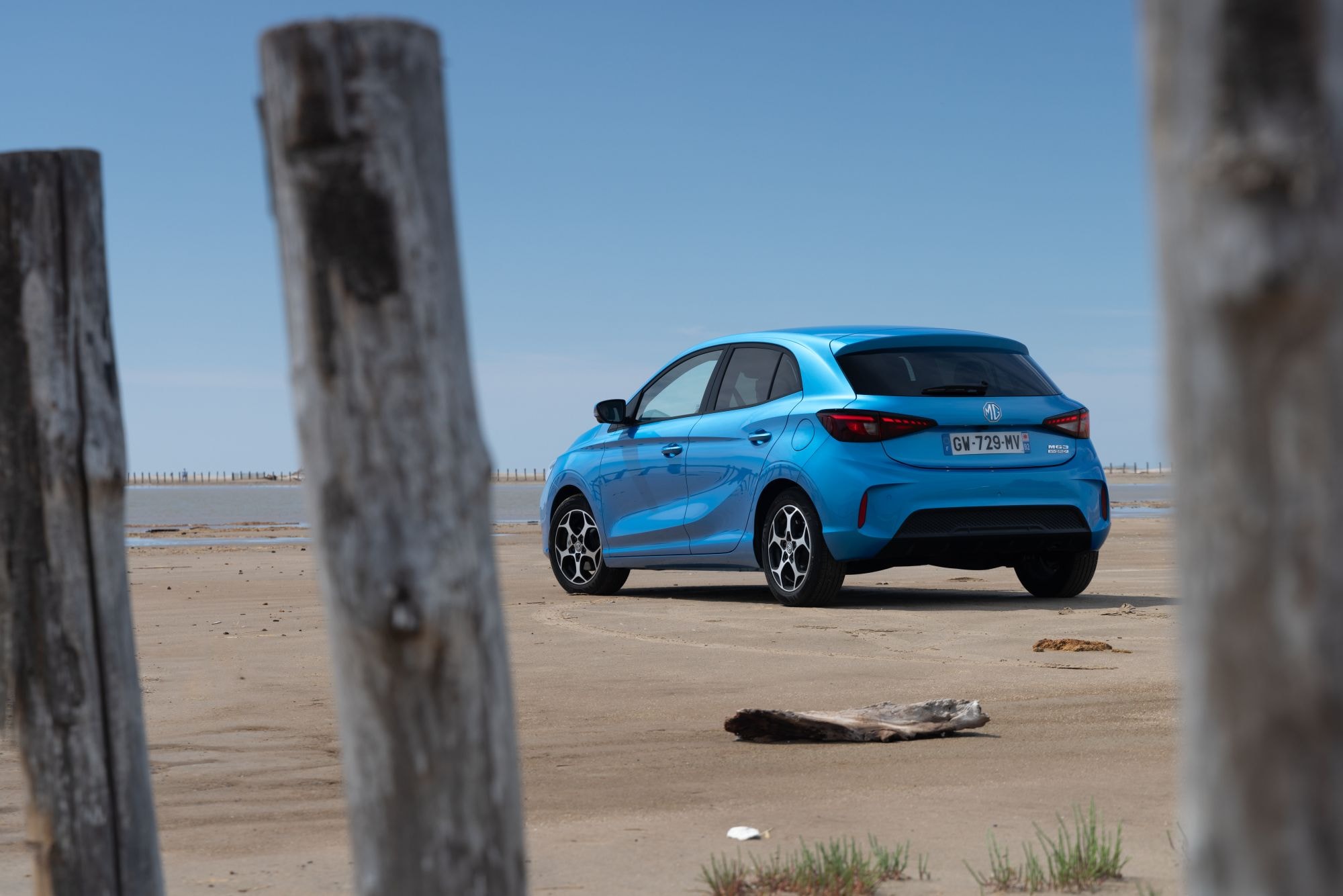MG 3 estacionado en la playa, exhibiendo su diseño y color vibrante.