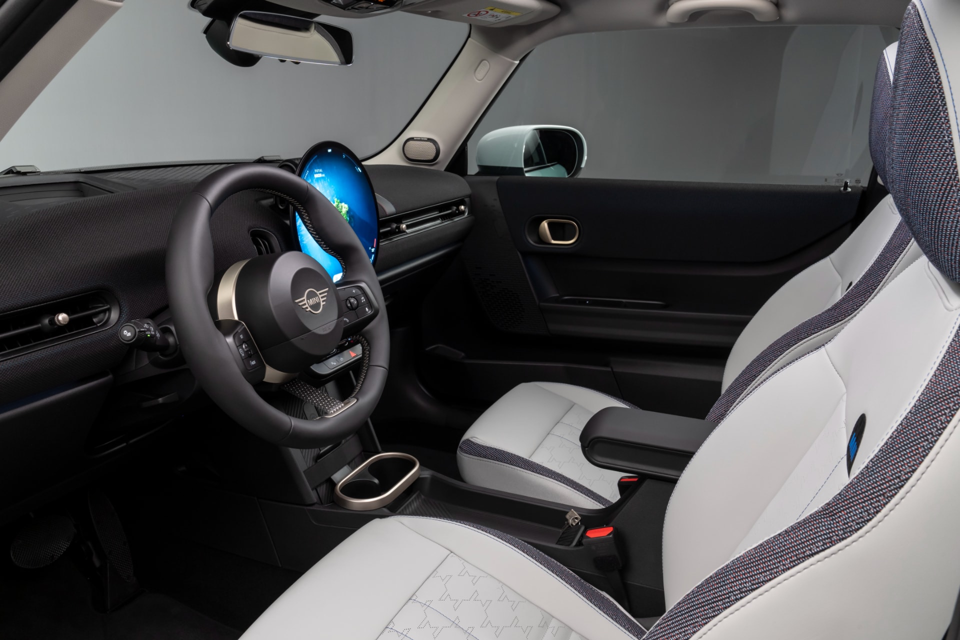 Interior del MINI Cooper SE con foco en los asientos delanteros y detalles azules.