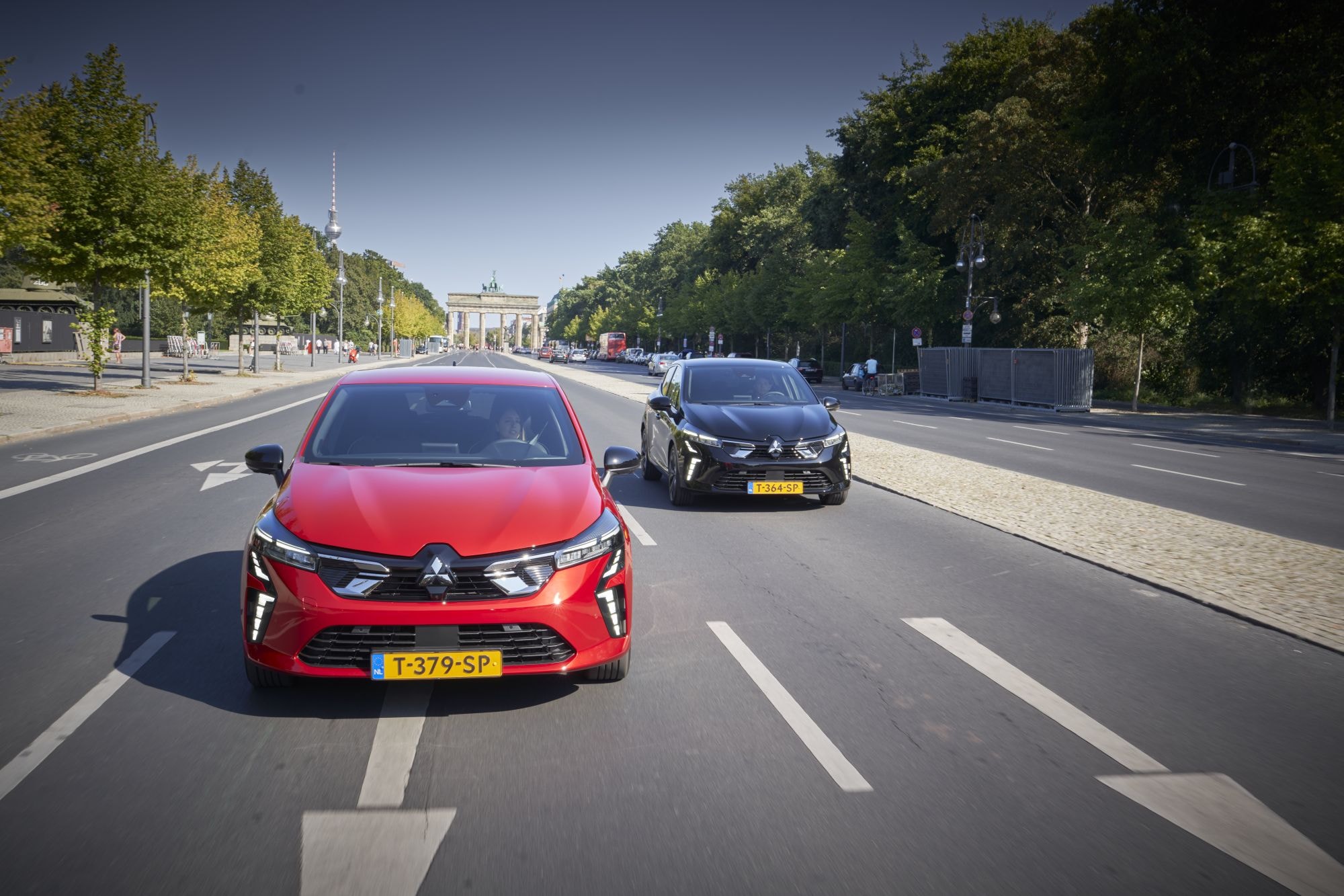Vista frontal del Mitsubishi Colt híbrido junto a un monumento emblemático.