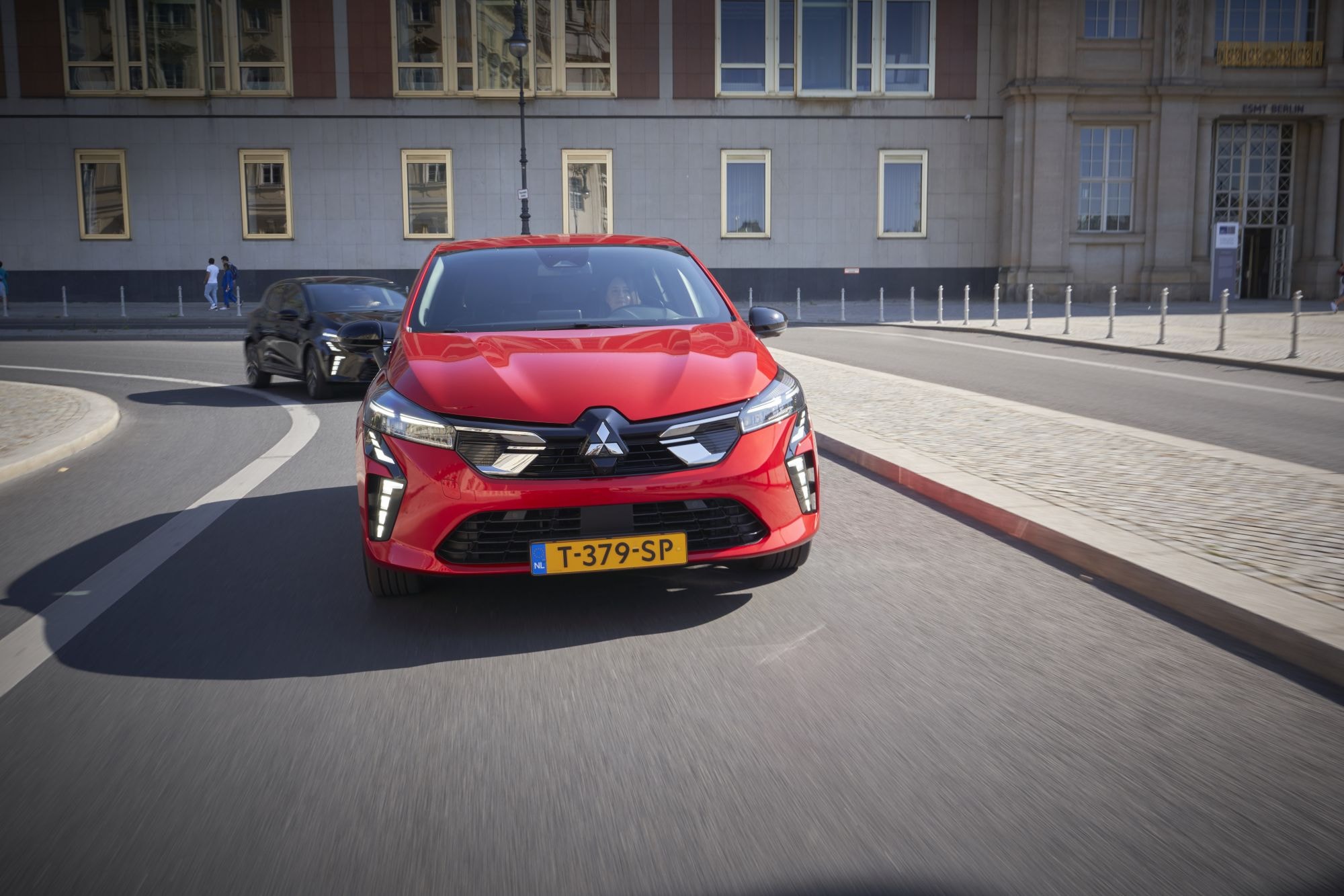 Mitsubishi Colt híbrido circulando en una elegante avenida de la ciudad.