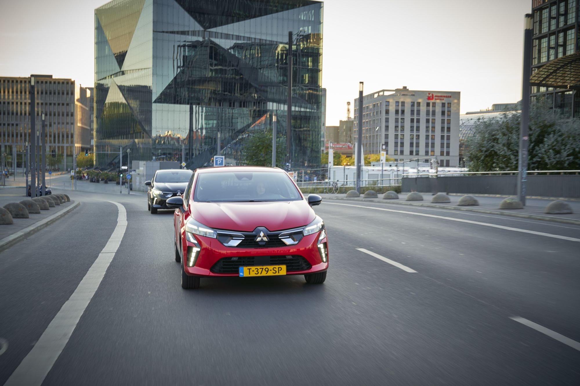 Mitsubishi Colt híbrido iluminado por la luz del atardecer en la ciudad.