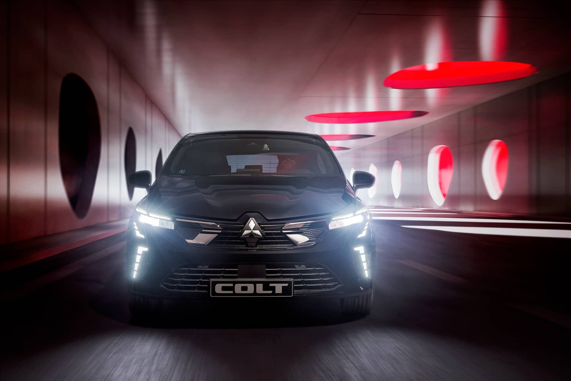 Vista frontal del Mitsubishi Colt pasando por un túnel futurista.