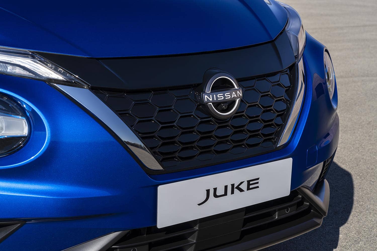 Primer plano de la parrilla del Nissan Juke híbrido, con énfasis en el emblema.