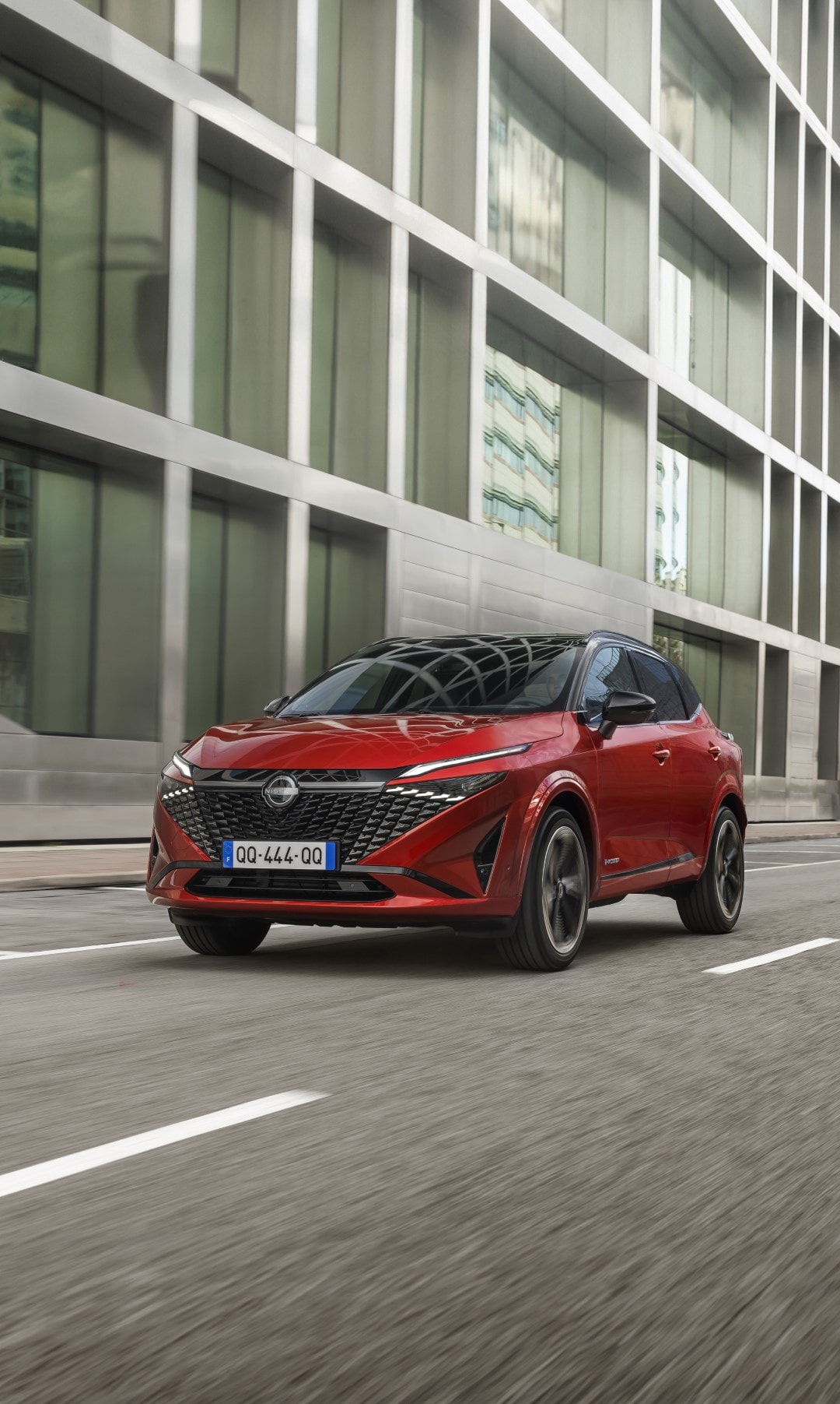 Nissan Qashqai híbrido avanzando, resaltando su aerodinámica en el entorno urbano.