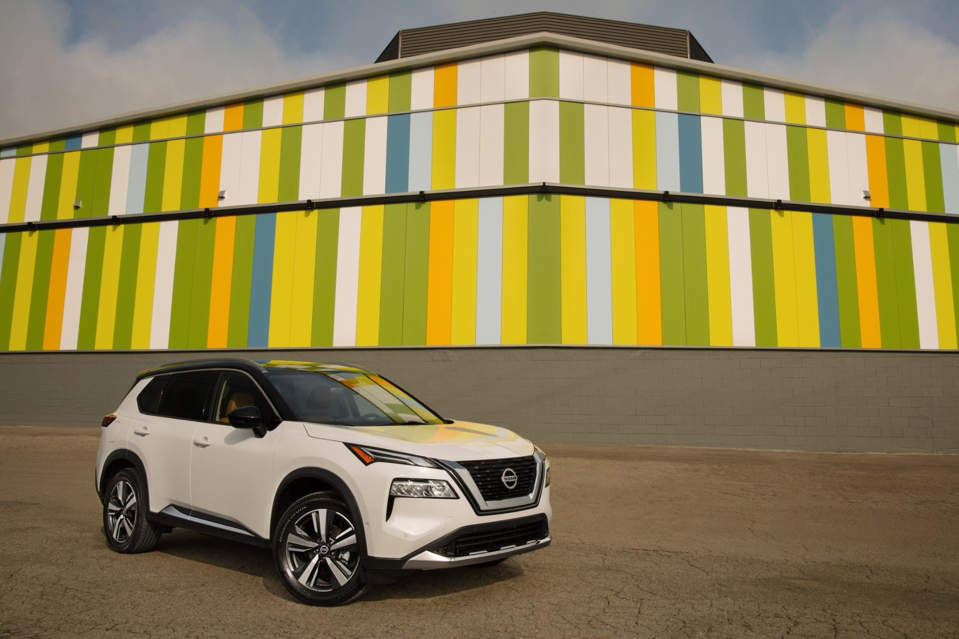 Nissan X-Trail híbrido frente a un fondo colorido, destacando su diseño frontal y trasero.