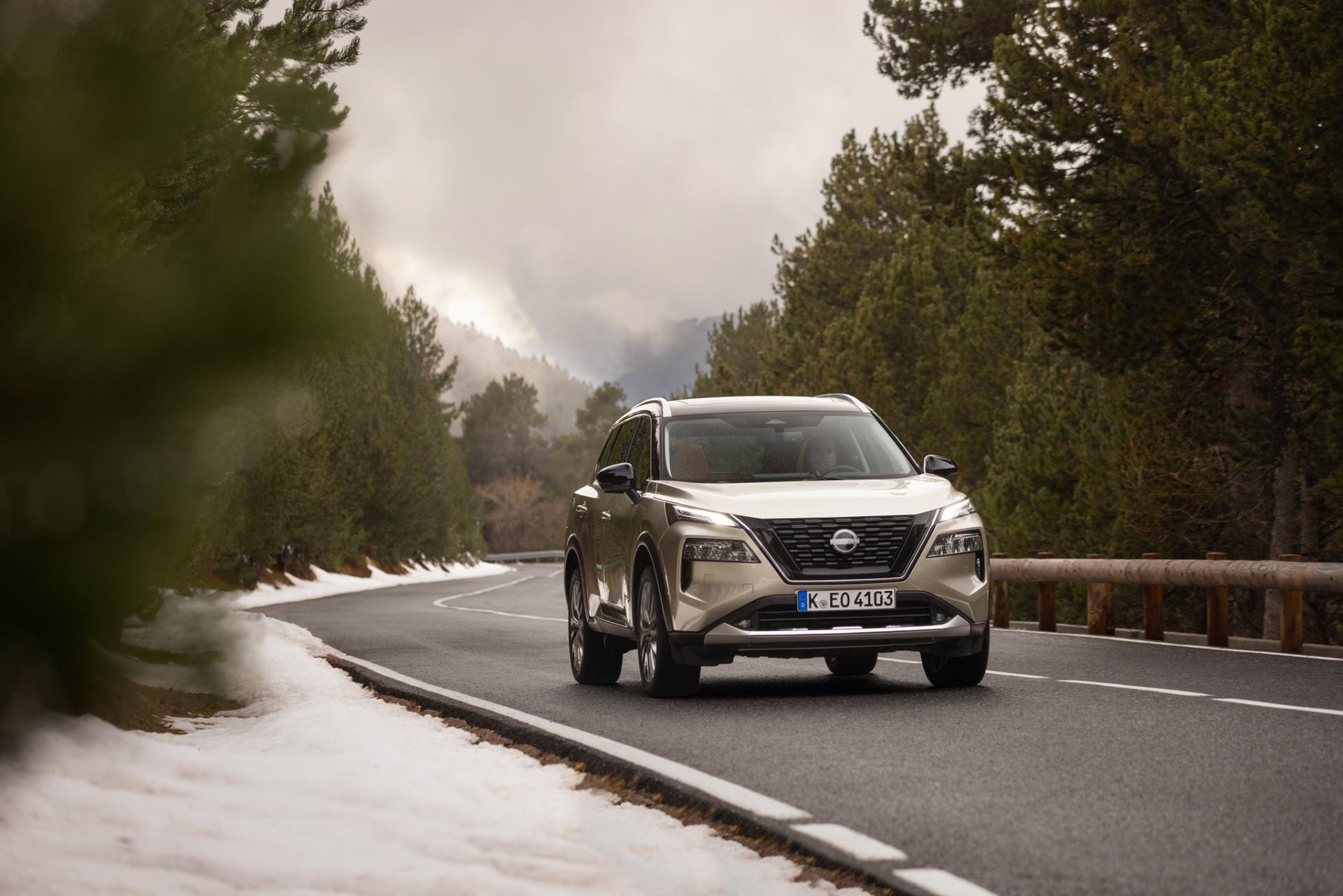 El Nissan X-Trail híbrido en acción, en una carretera con un paisaje de invierno al fondo.