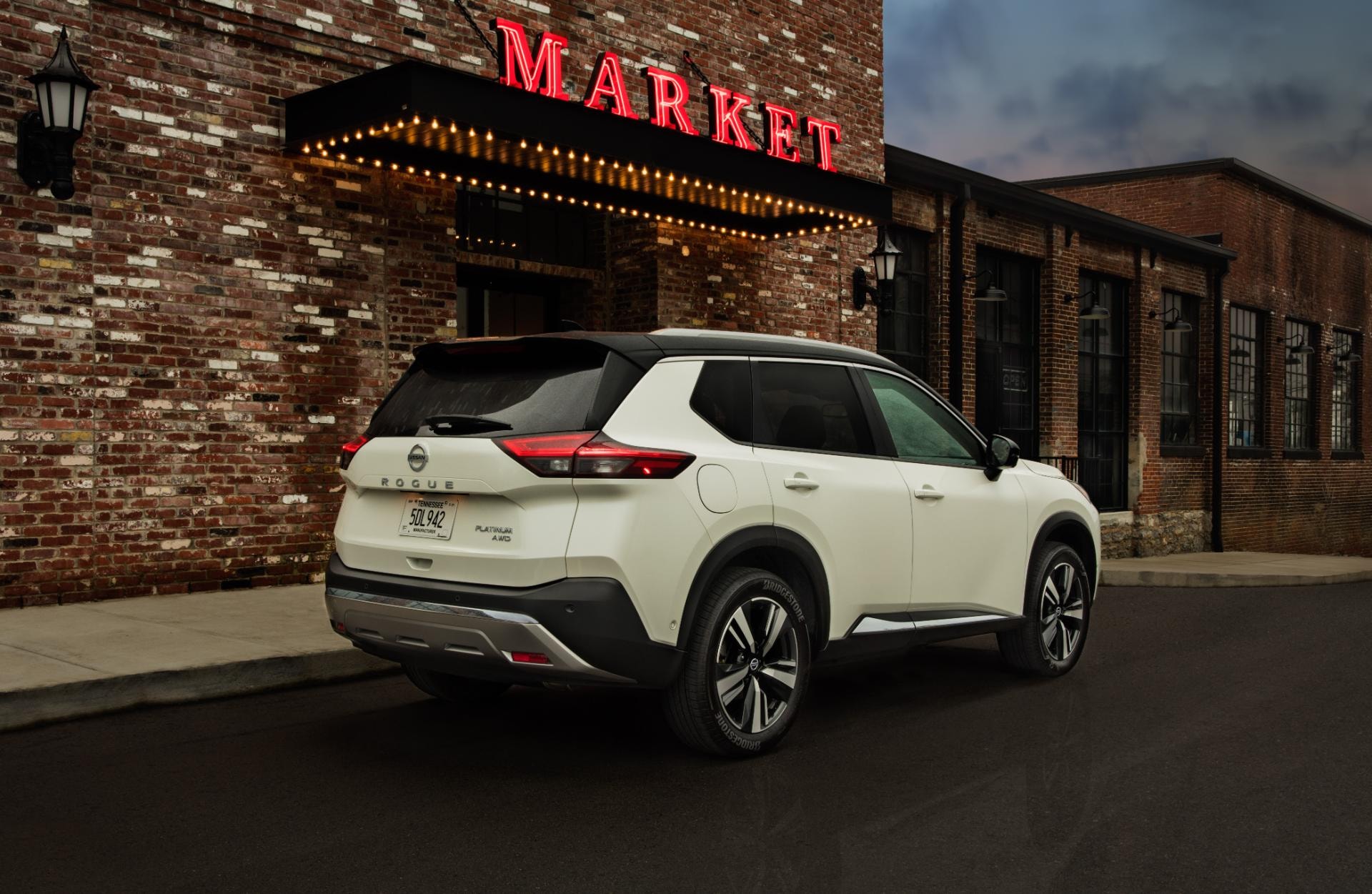 La trasera del Nissan X-Trail híbrido iluminada por la luz de neón de un mercado.