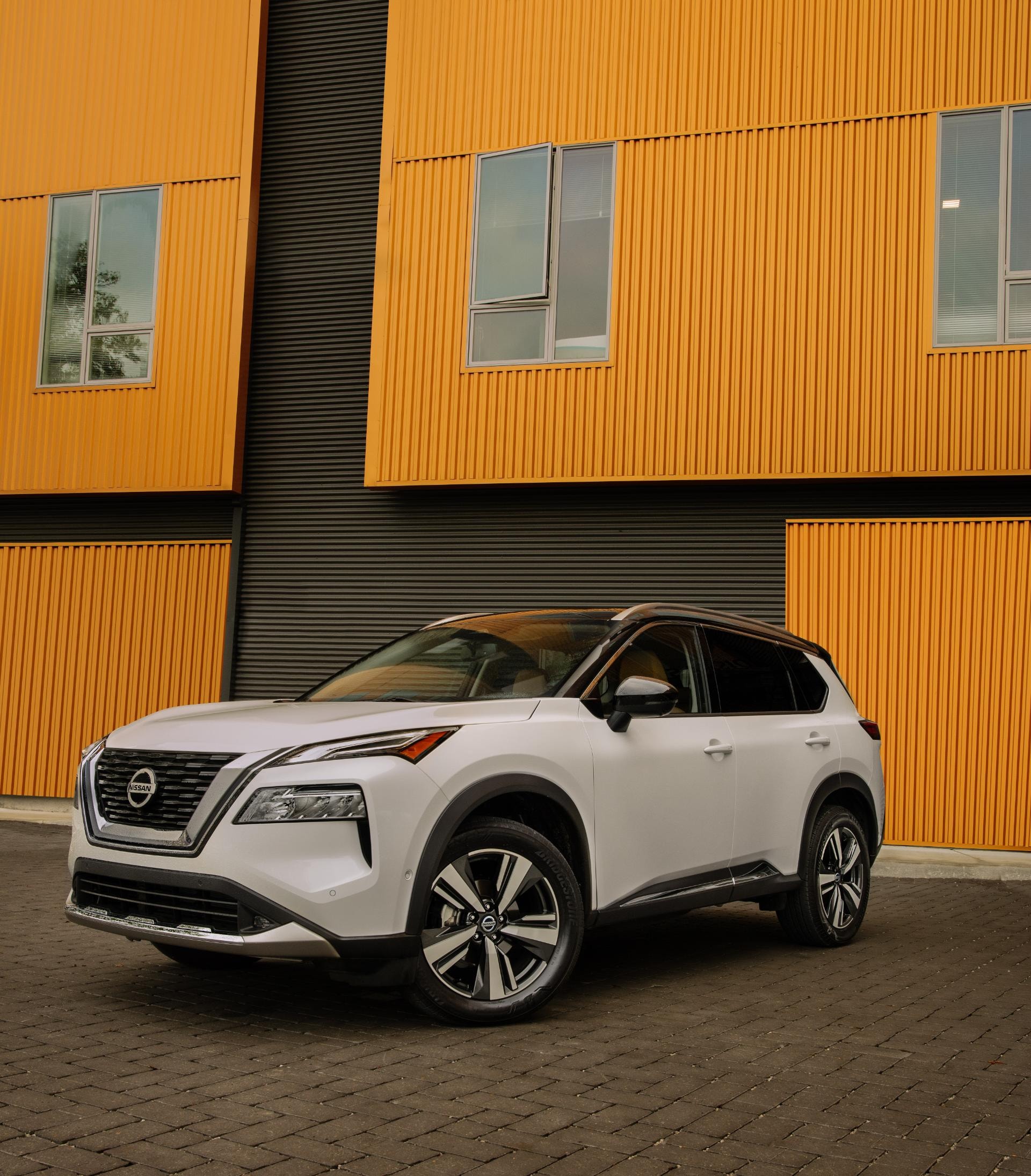 Nissan X-Trail híbrido capturado desde una perspectiva frontal cerca de un edificio contemporáneo.