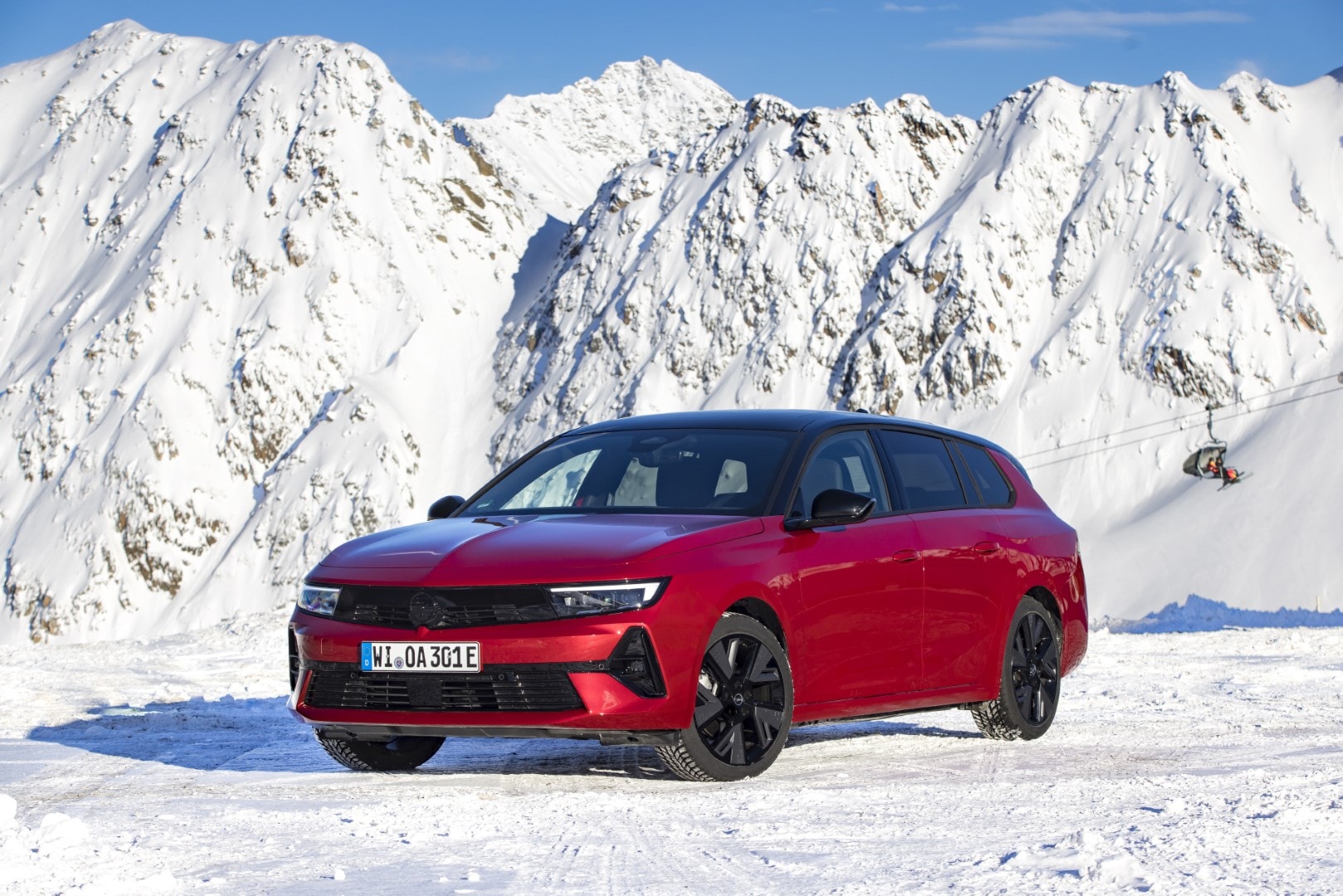 Vista dinámica frontal lateral del Opel Astra Sports Tourer en paisaje nevado.