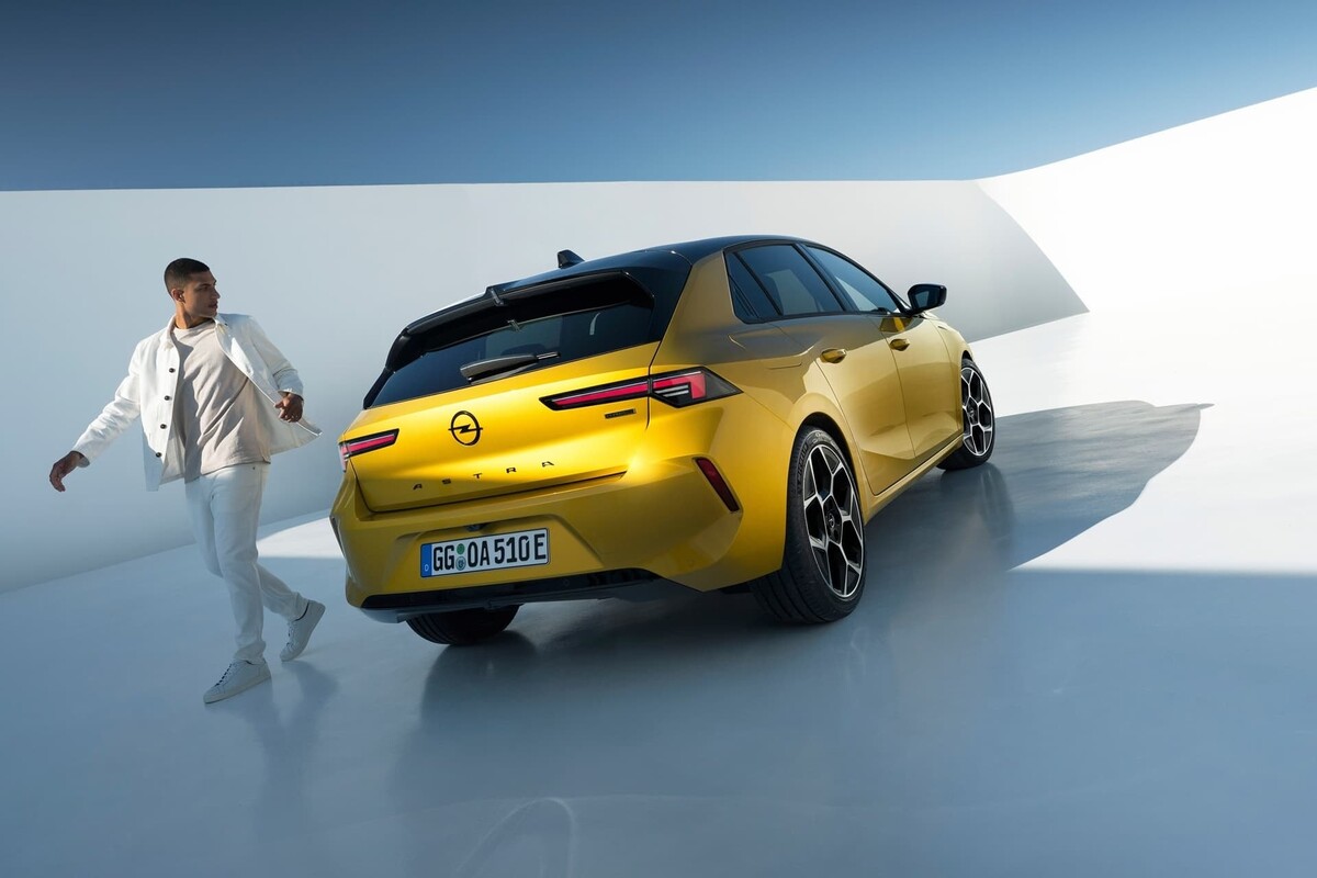 Vista de tres cuartos trasera del Opel Astra con una persona apoyada en él. Vista de tres cuartos trasera del Opel Astra con una persona apoyada en él.