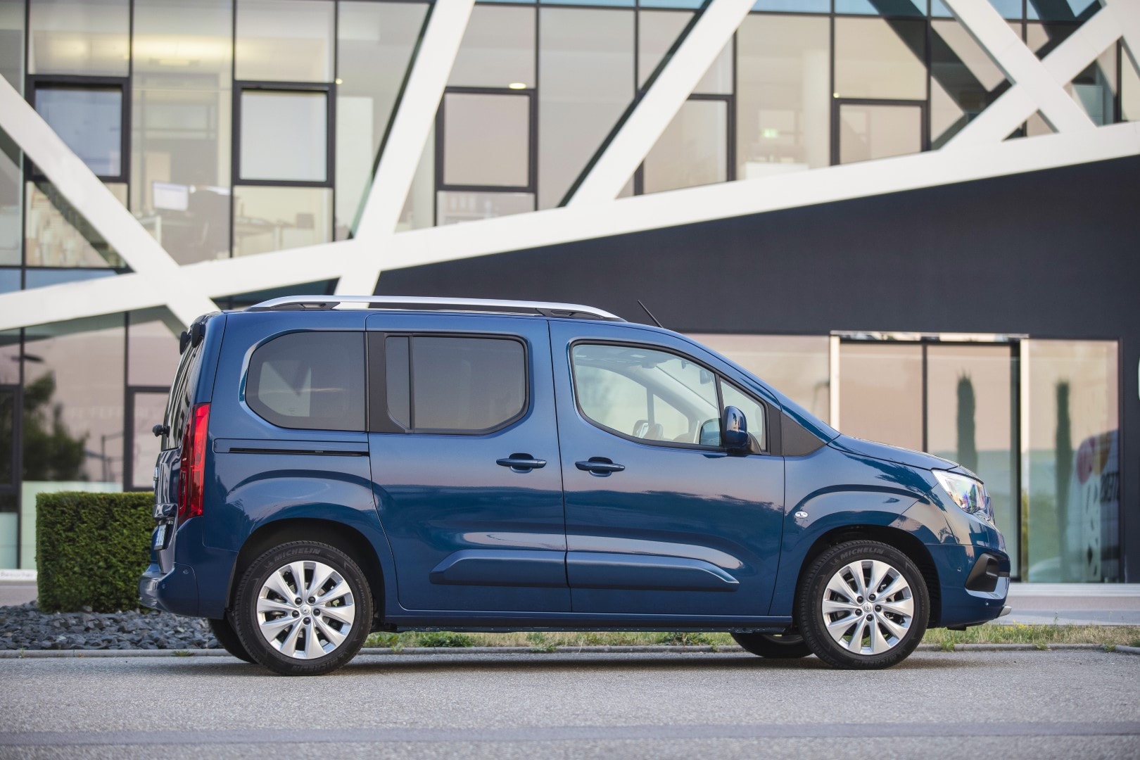 Vista lateral del Opel Combo Life aparcado frente a un edificio moderno.